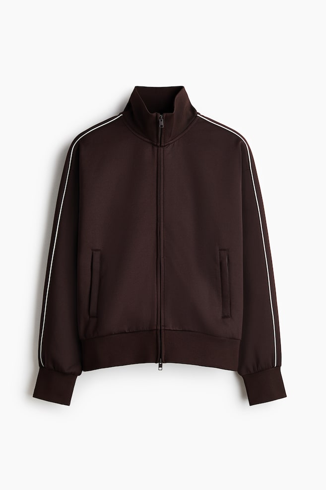 Eine braune Trainingsjacke, wie FRONT, verfügt über einen Stehkragen, einen durchgehenden Reißverschluss und zwei vordere Eingrifftaschen. Weiße Streifen verlaufen entlang der äußeren Nähte beider Ärmel, und gerippte Bündchen sowie ein gerippter Saum sind vorhanden. - 1
