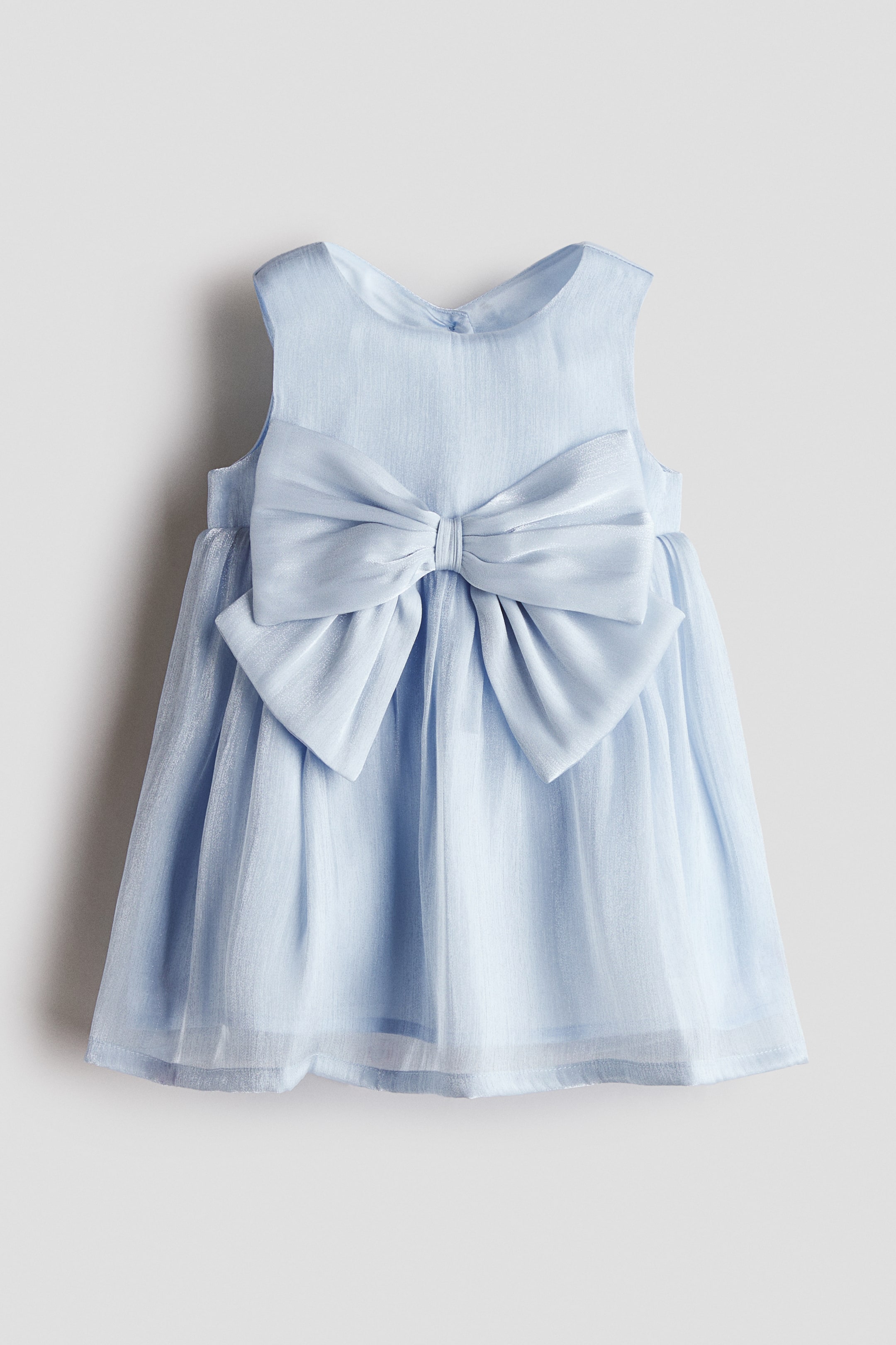 View larger image: The light blue sleeveless dress is positioned front-facing, showcasing a round neckline and a prominent satin bow at the waist. Gathers contribute to a voluminous, sheer organza skirt.