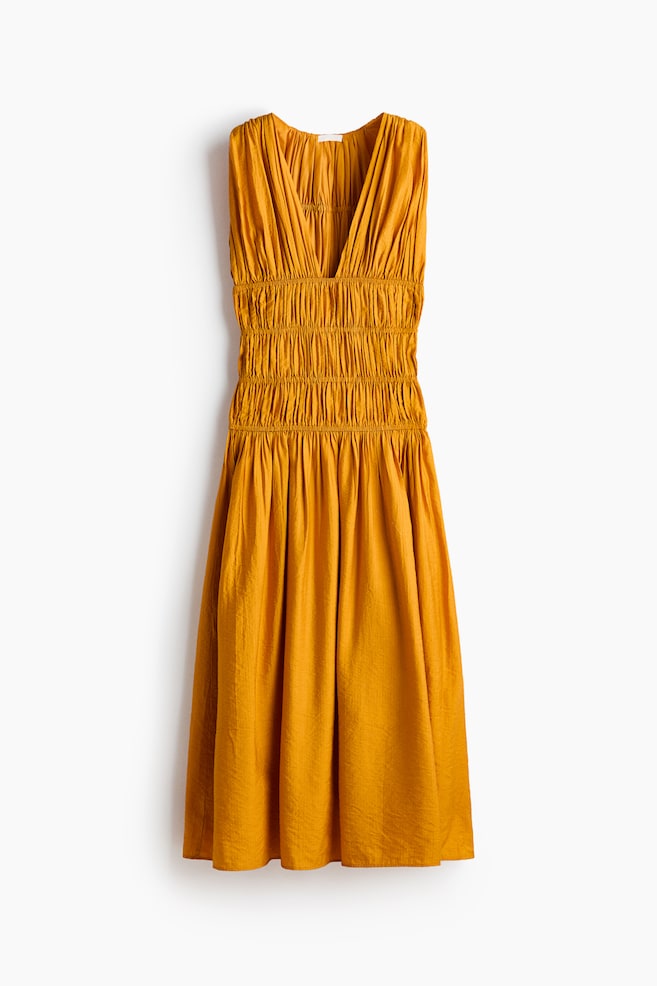 The mustard yellow sleeveless dress is featuring a deep V-neckline, a shirred bodice, and a flowing A-line skirt, seen from the front, with the fabric displaying a subtle crinkled texture. - 1