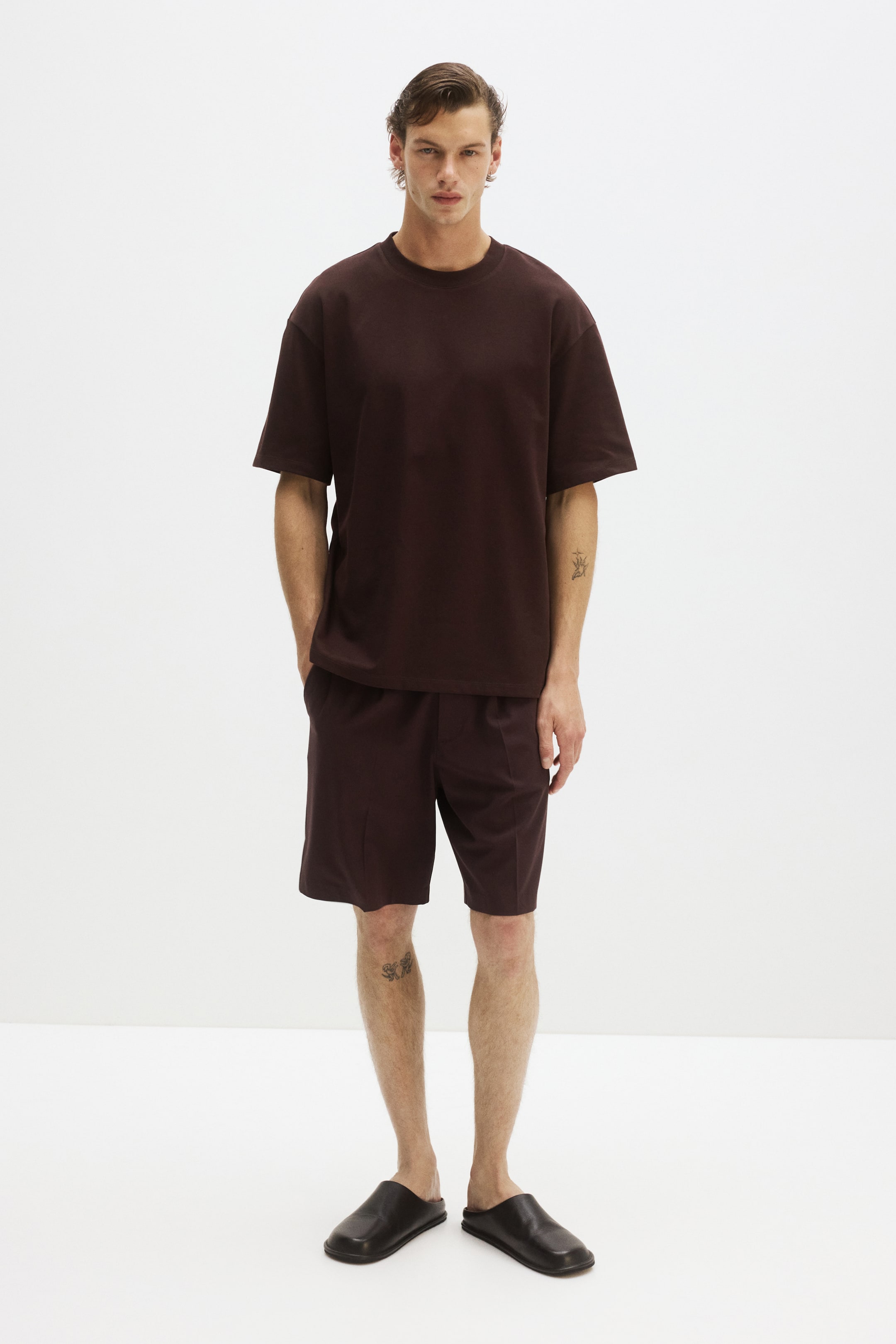 View larger image: A dark brown, relaxed-fit T-shirt, featuring a round, rib-trimmed neckline, dropped shoulders, short sleeves, and a straight-cut hem, is being worn by the model.