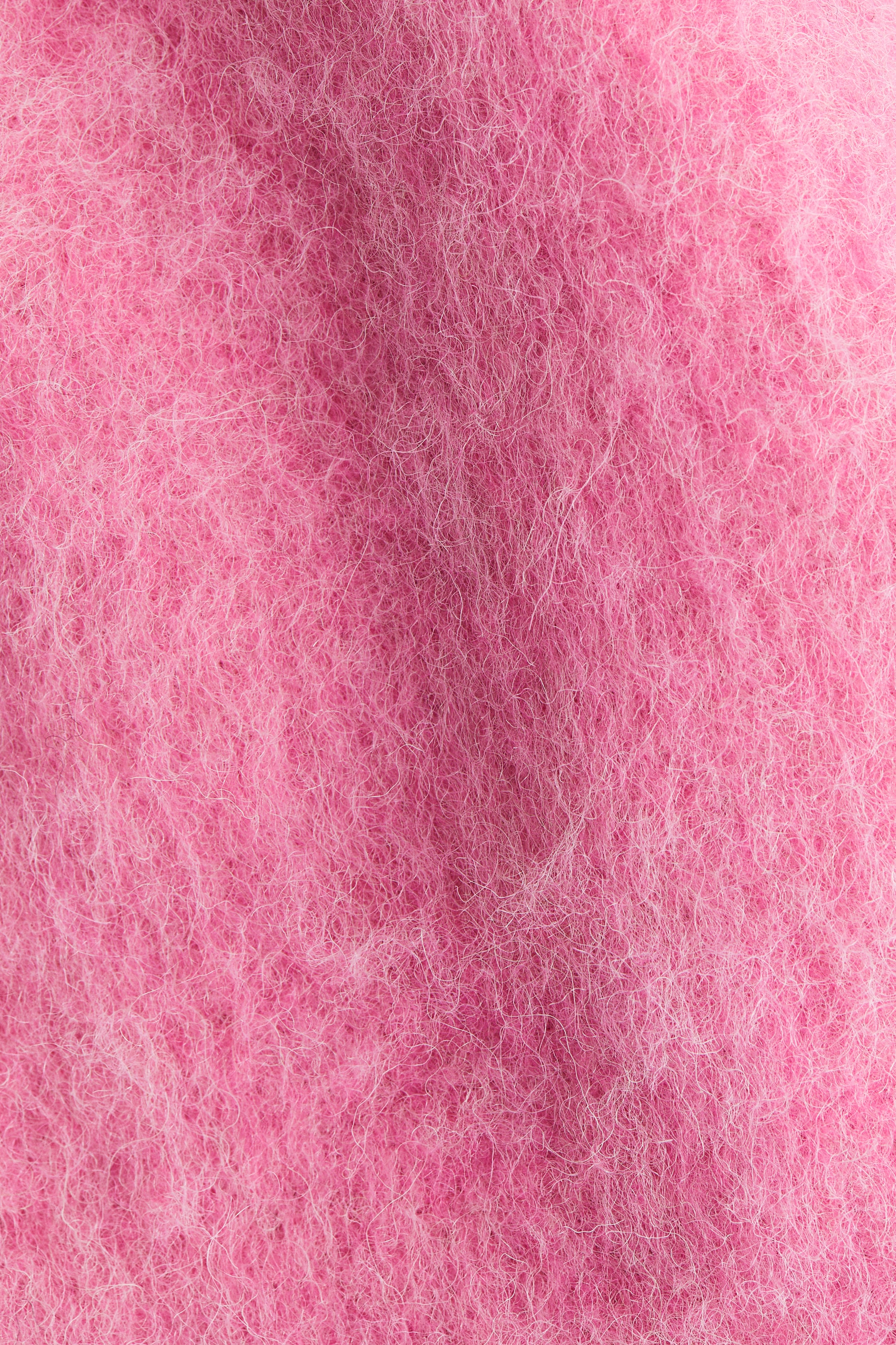 View larger image: The product is a vibrant pink textile, exhibiting a dense, fuzzy texture with numerous fine, light-colored fibers. It is creating a soft, uneven surface.