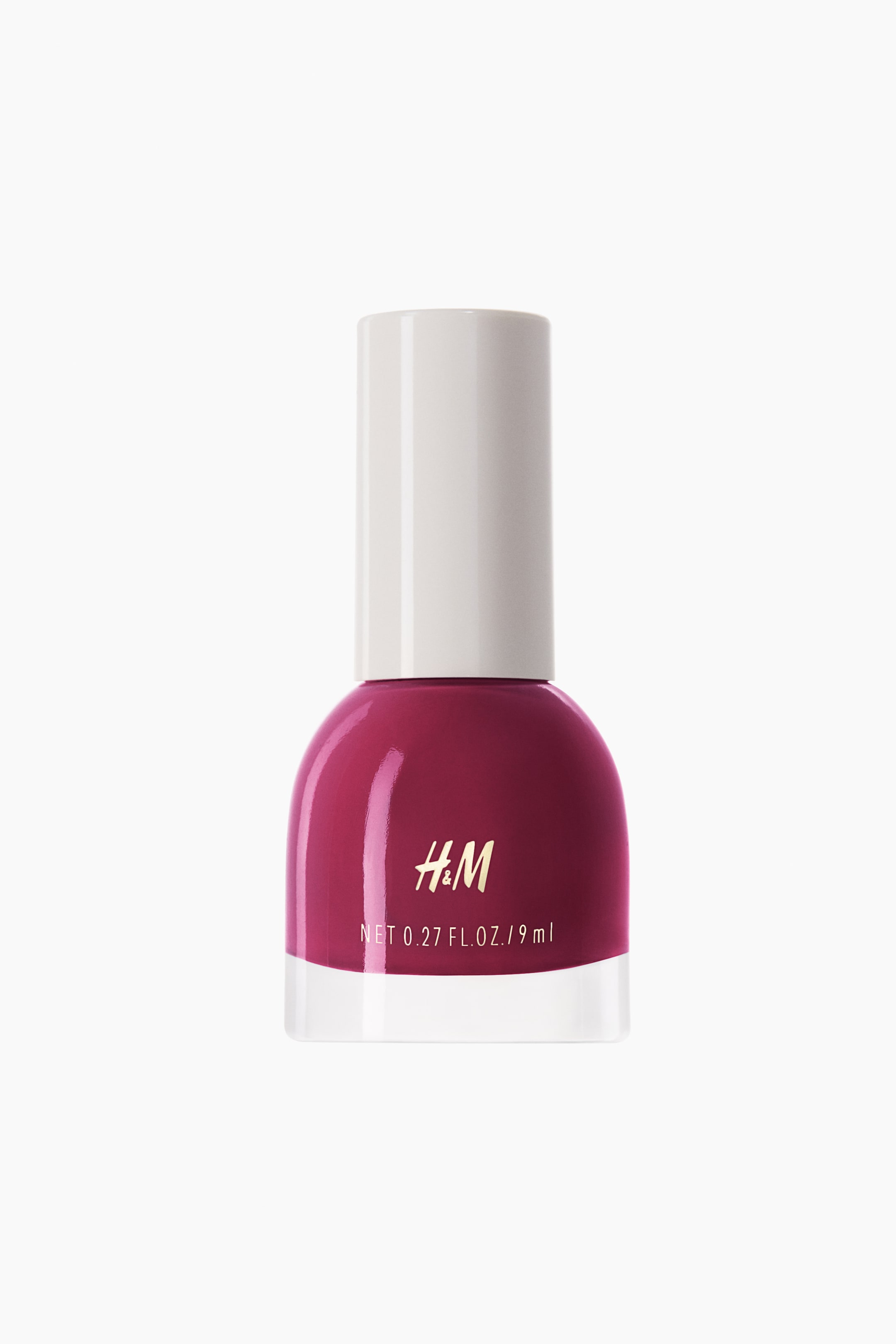 View larger image: The nail polish is positioned upright, with its transparent glass bottle containing a rich magenta polish. A white cylindrical cap sits atop, sealing it. The H&M logo and net weight are displayed prominently on the front of the bottle.
