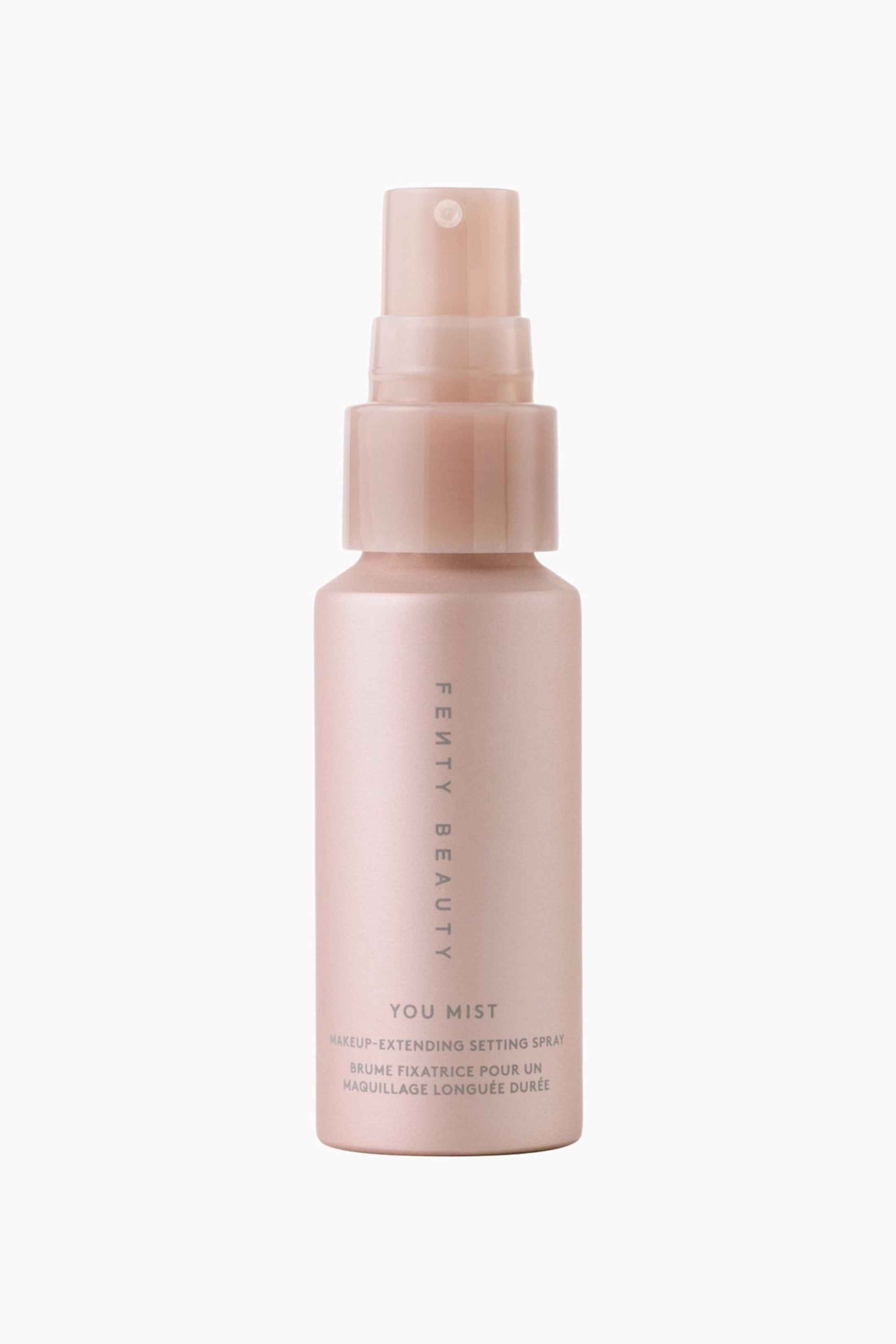 Näytä suurempi kuva: You Mist Makeup -meikin kestävyyttä pidentävä setting spray on asetettu pystyasentoon, ja siinä on helmiäishohtoinen vaaleanpunainen sylinterimäinen pullo sekä siihen sopiva porrastettu suihkepumppu. Etupuolelta kuvattu pullo esittelee pystysuuntaista "FENTY BEAUTY"-brändäystä ja tuotetiedot harmaalla tekstillä.