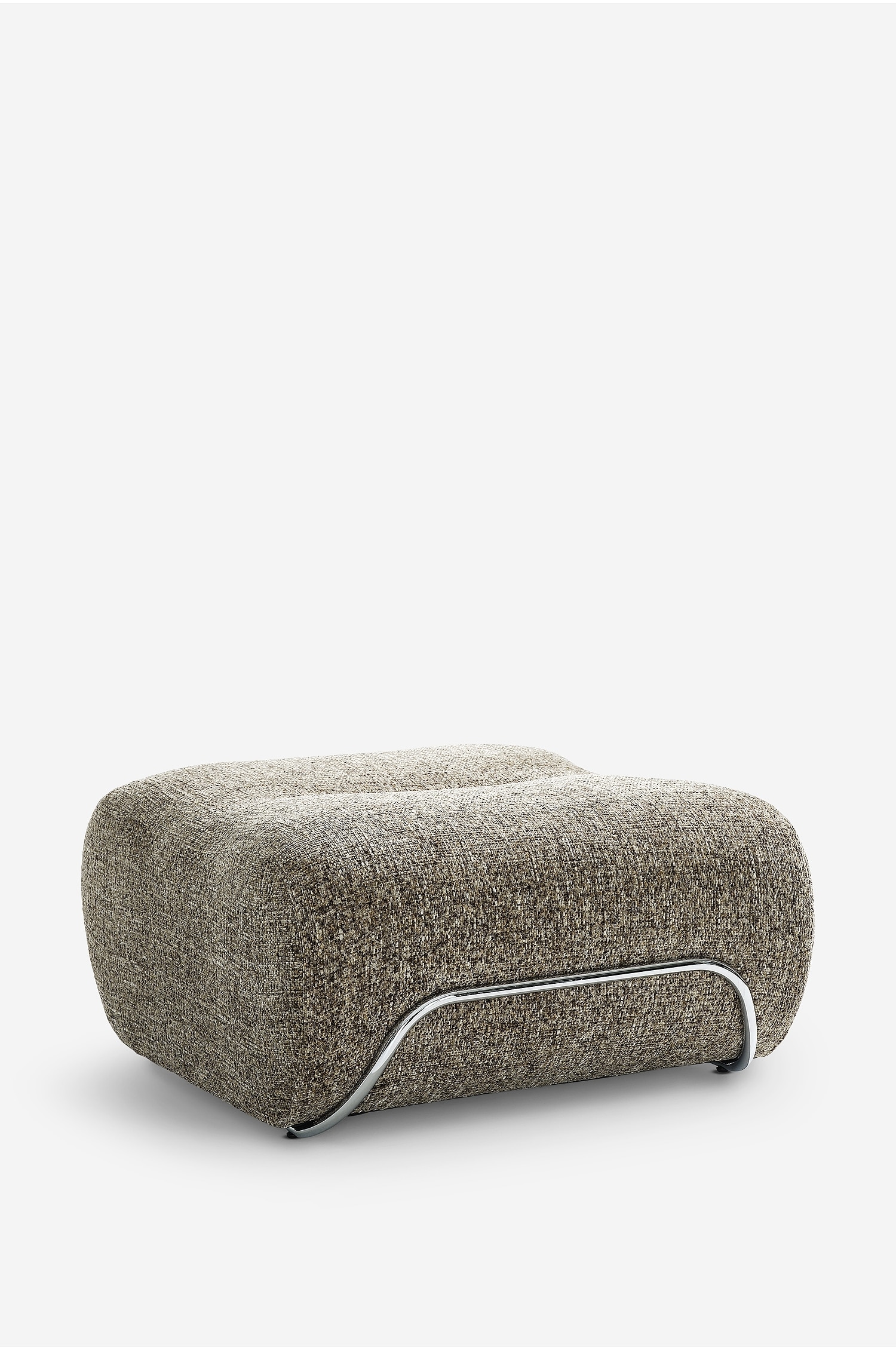 De Archie Pouf staat in een driekwartaanzicht en toont zijn laag profiel, afgeronde rechthoekige ontwerp, bekleed met een gestructureerde, meerkleurige bruine en beige geweven stof. Langs de onderrand is een gebogen, buisvormig frame in chroommetaal aangebracht voor extra steun, terwijl op het bovenoppervlak een klein decoratief keramisch schaaltje met roze bloemen rust.
