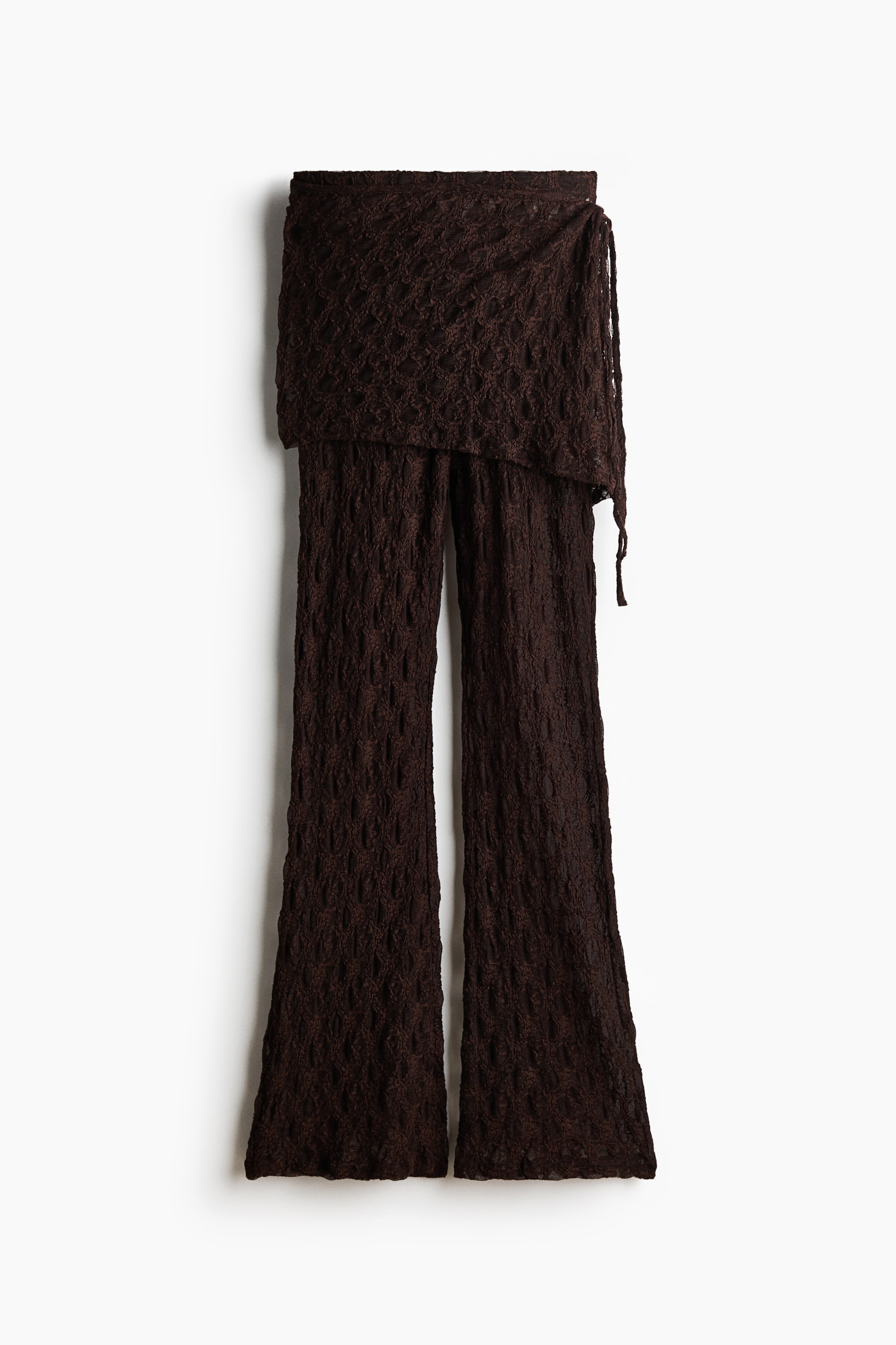 View larger image: A pair of dark brown wide-leg pants is shown from the front, featuring a wrap-around overlay at the waist with a tie closure. The overlay displays an open-knit pattern, while the pant legs show a crinkled texture.
