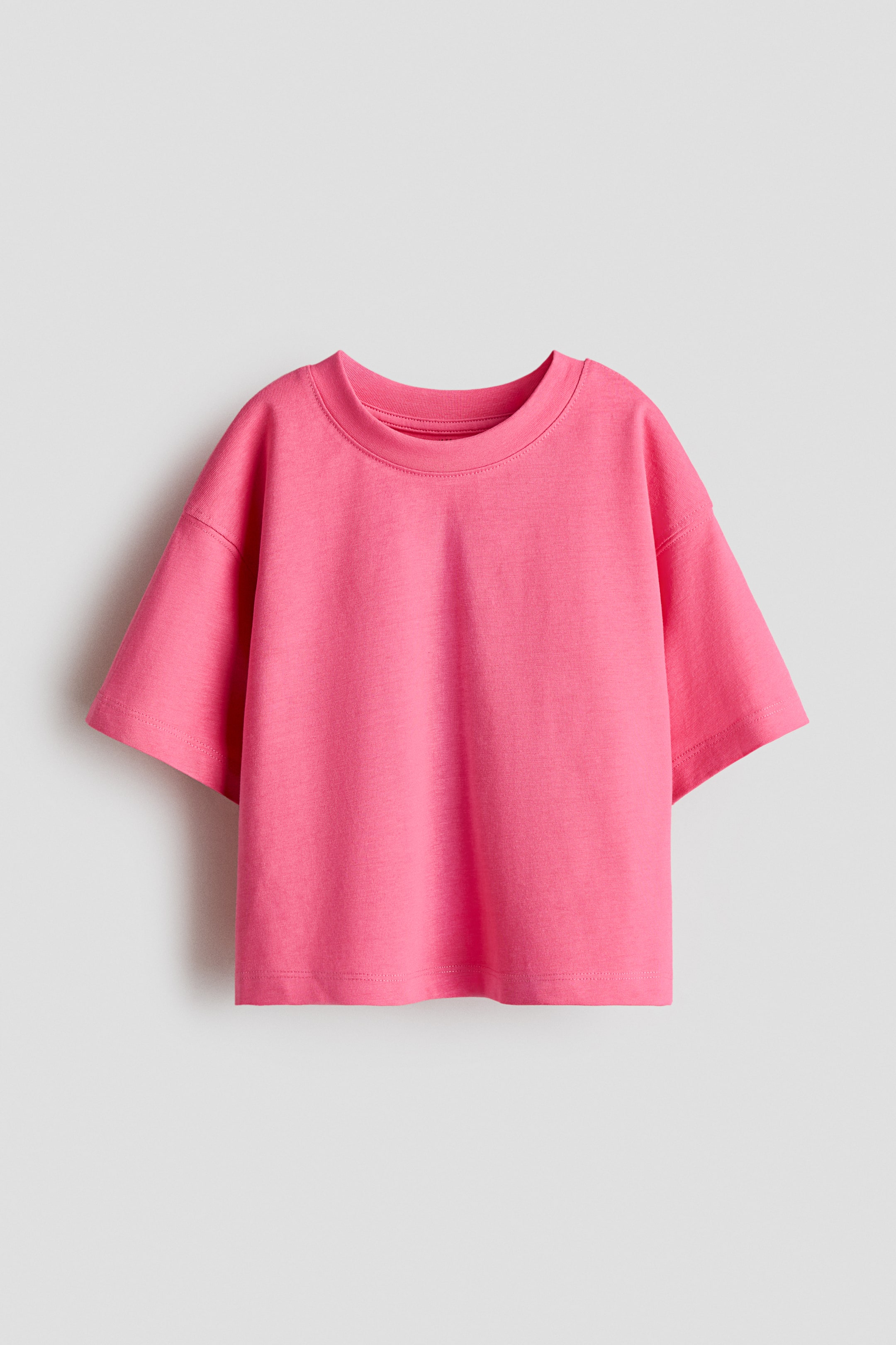 View larger image: A pink, loose-fit, boxy-style T-shirt, made from soft cotton jersey, showcases its front design with a round, ribbed neckline and dropped shoulders.