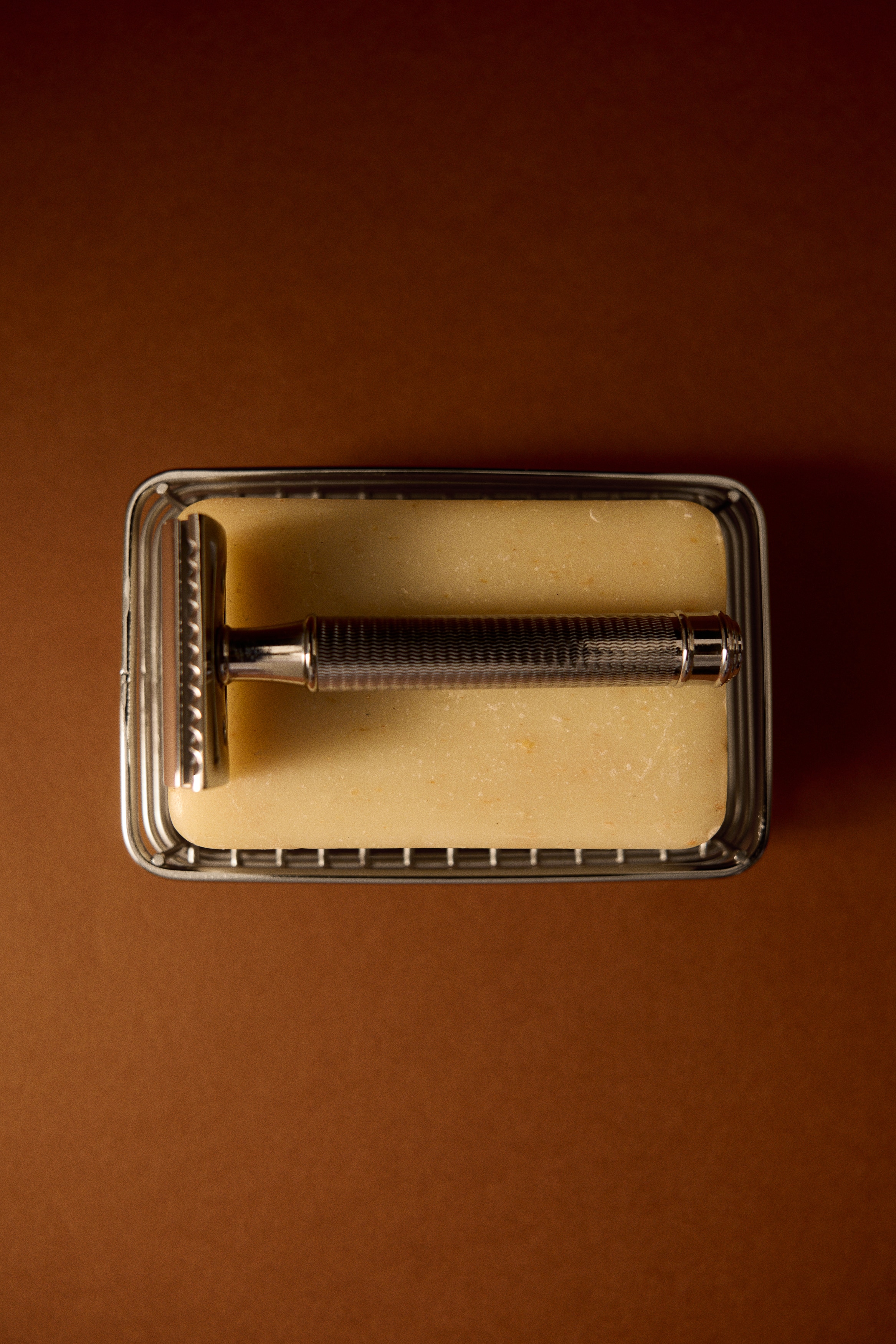 The rectangular metal caddy features a shiny open-wire design with rounded corners, showing a slatted base and parallel bars forming its sides, presented from a three-quarter front view.