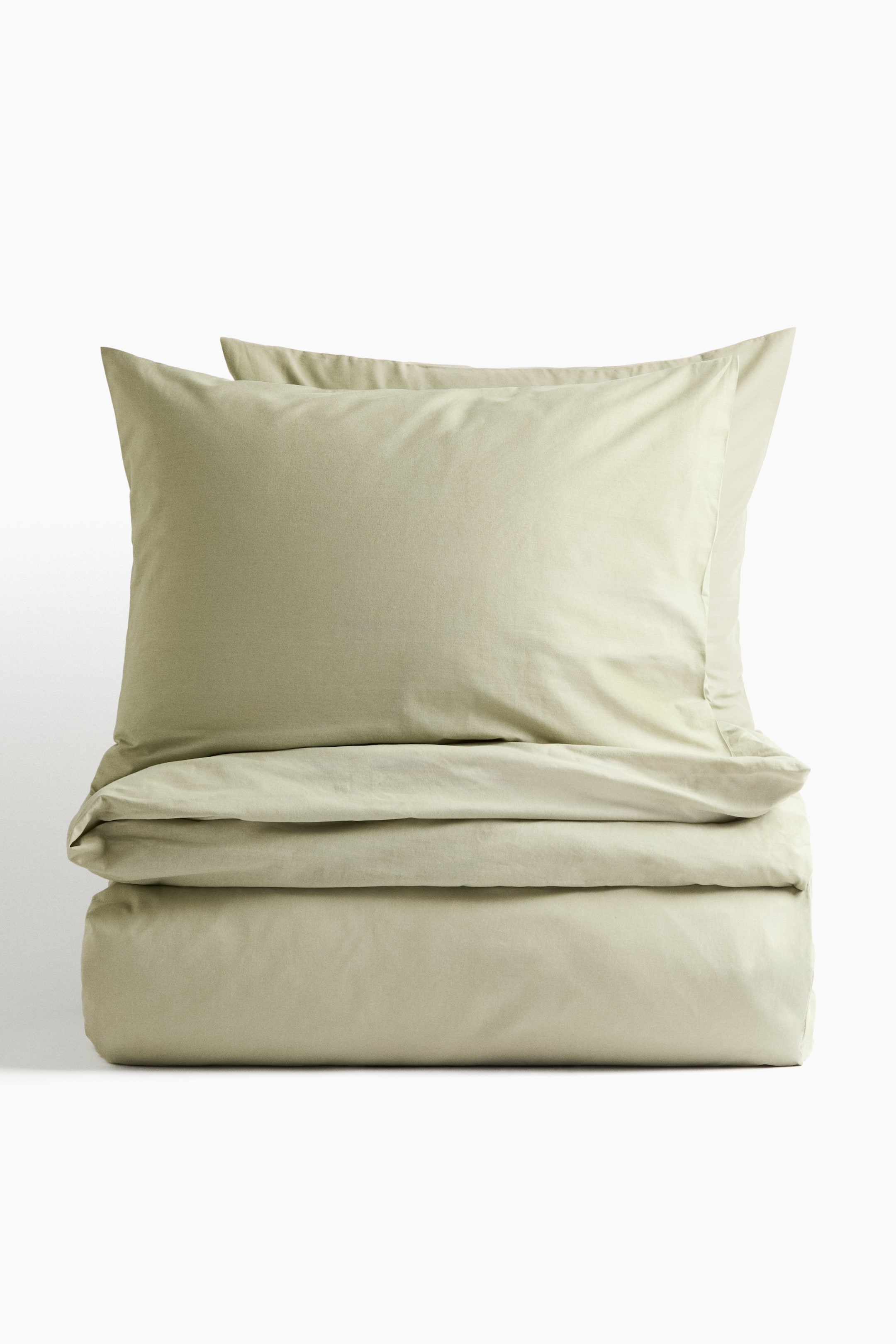 View larger image: A light green double duvet cover set is displayed, featuring a horizontally folded duvet cover with two stacked pillowcases on top.