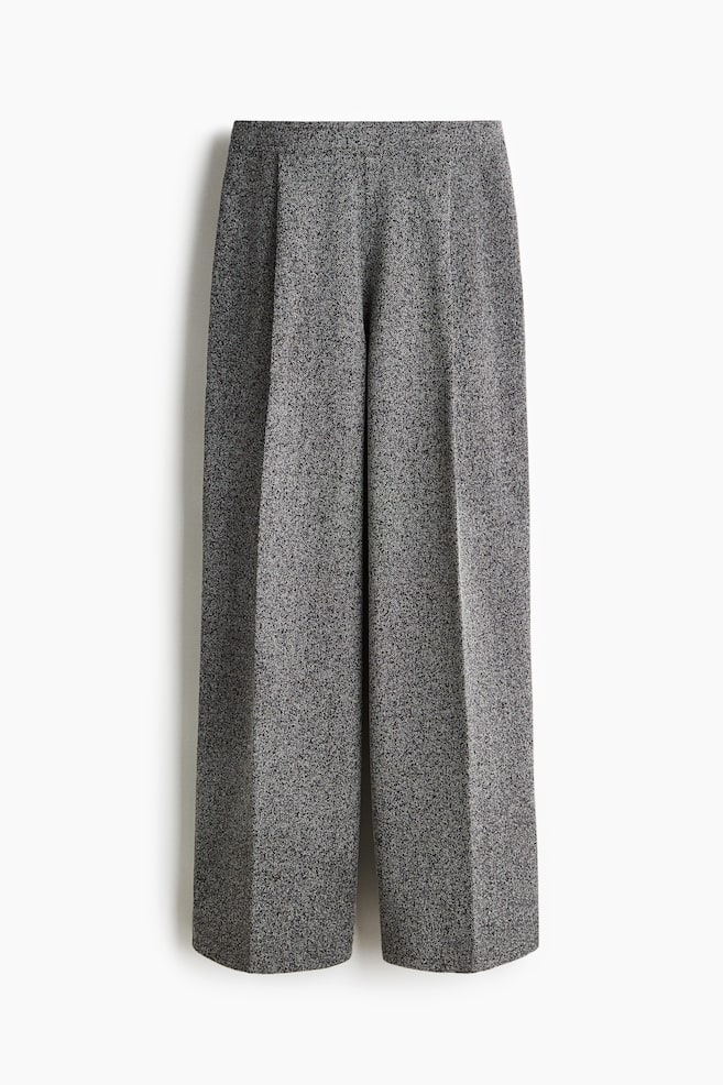 A pair of grey wide-leg pants is displayed from the front, featuring a speckled, marled fabric texture. Sharp, pressed creases are running down the front of each leg, and the waistband is smooth and flat. - 1