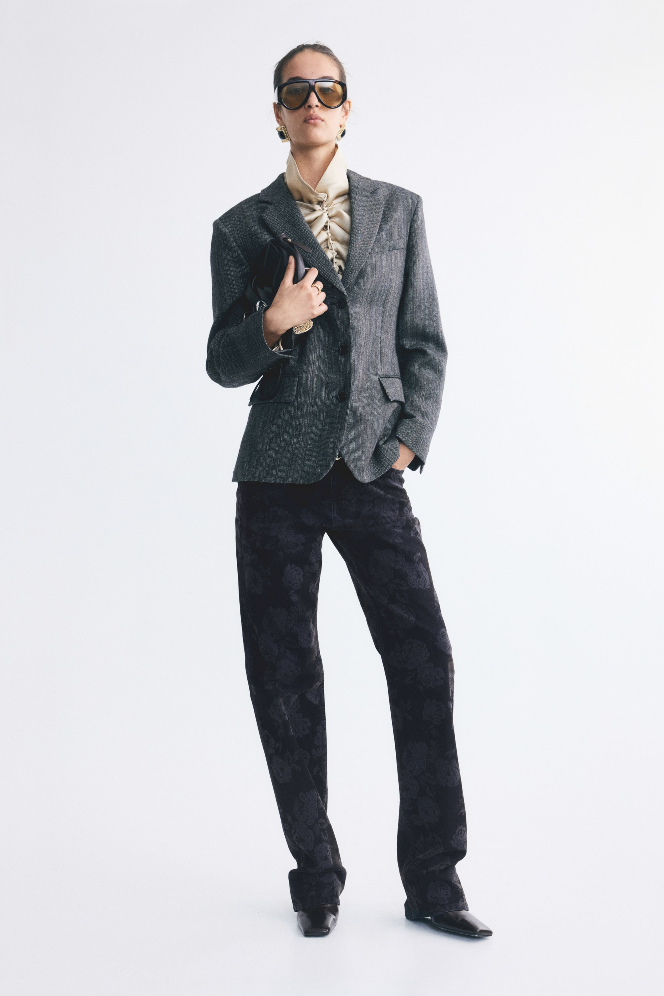 View larger image: Straight-leg denim jeans in a dark wash featuring an all-over floral flocked print are worn by the model. The jeans are styled with a gray structured blazer, a ruffled cream blouse, and black pointed-toe shoes.