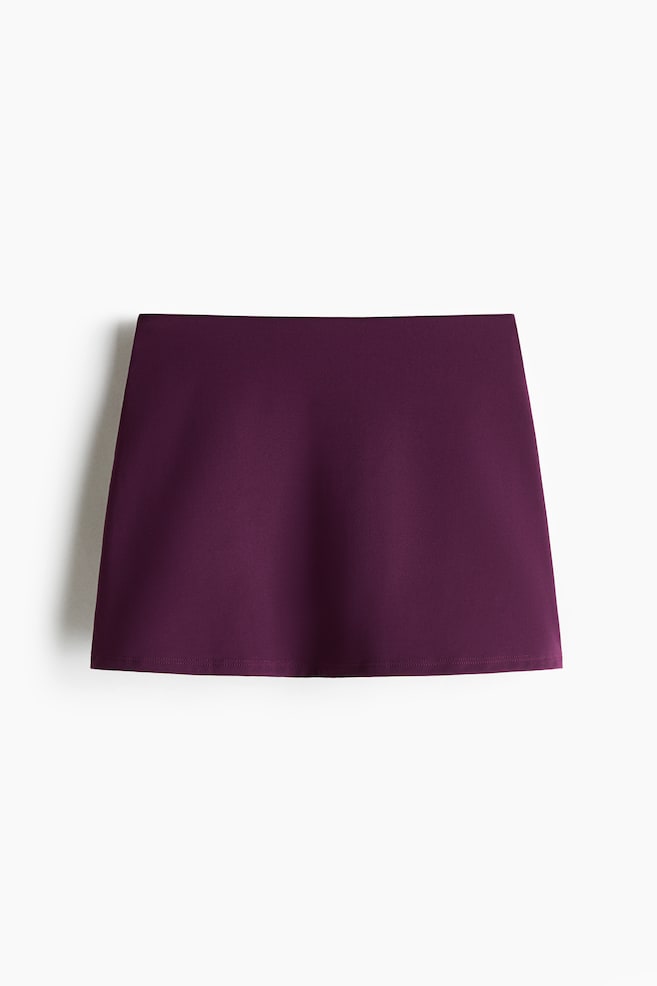 A tennis skirt is featuring a deep plum color, a smooth fabric, and an A-line silhouette, facing front. - 1