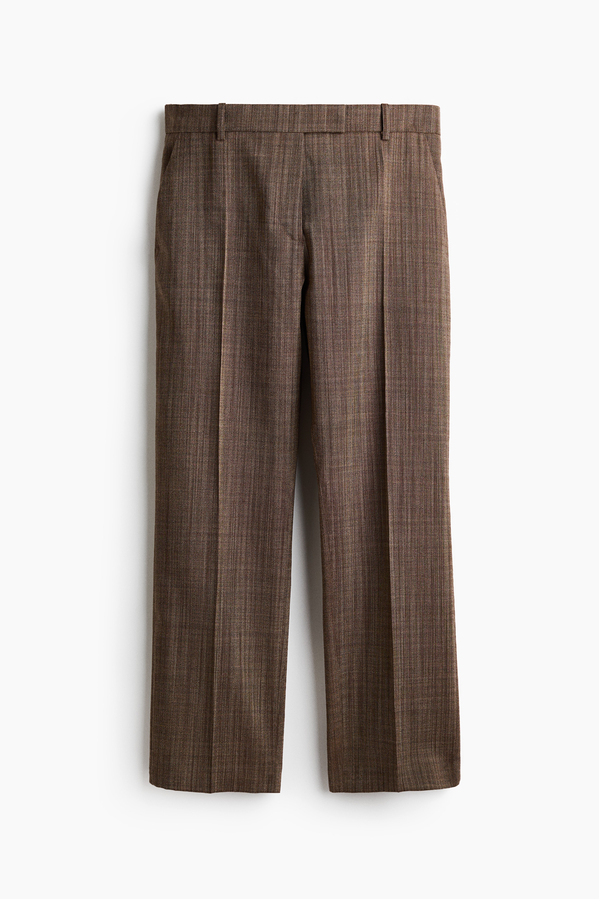 Brown wool-weave trousers featuring slightly tapered legs with creases down the front are worn by the model. The trousers are styled with a matching double-breasted blazer and black heeled mules, with the model placing a hand in the pocket.
