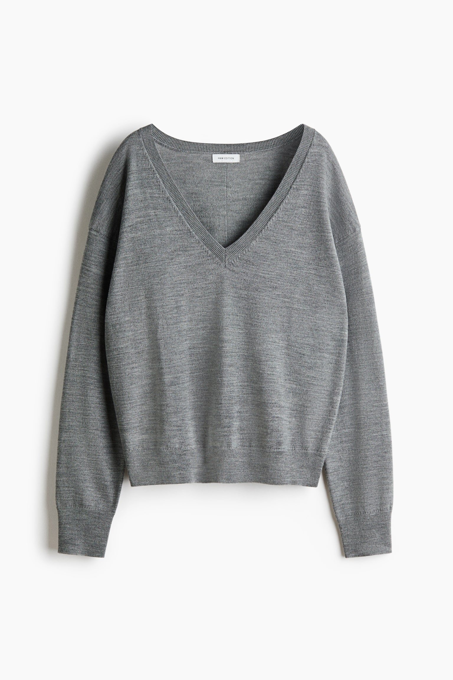 Ein grauer Strickpullover wird von vorne gezeigt und verfÃ¼gt Ã¼ber einen tiefen V-Ausschnitt mit RippenbÃ¼ndchen sowie Ã¼berschnittene Schultern. Der Pullover prÃ¤sentiert sich in lockerer Passform mit langen Ãrmeln, die mit gerippten BÃ¼ndchen abschlieÃen, und einem passenden gerippten Saum.
