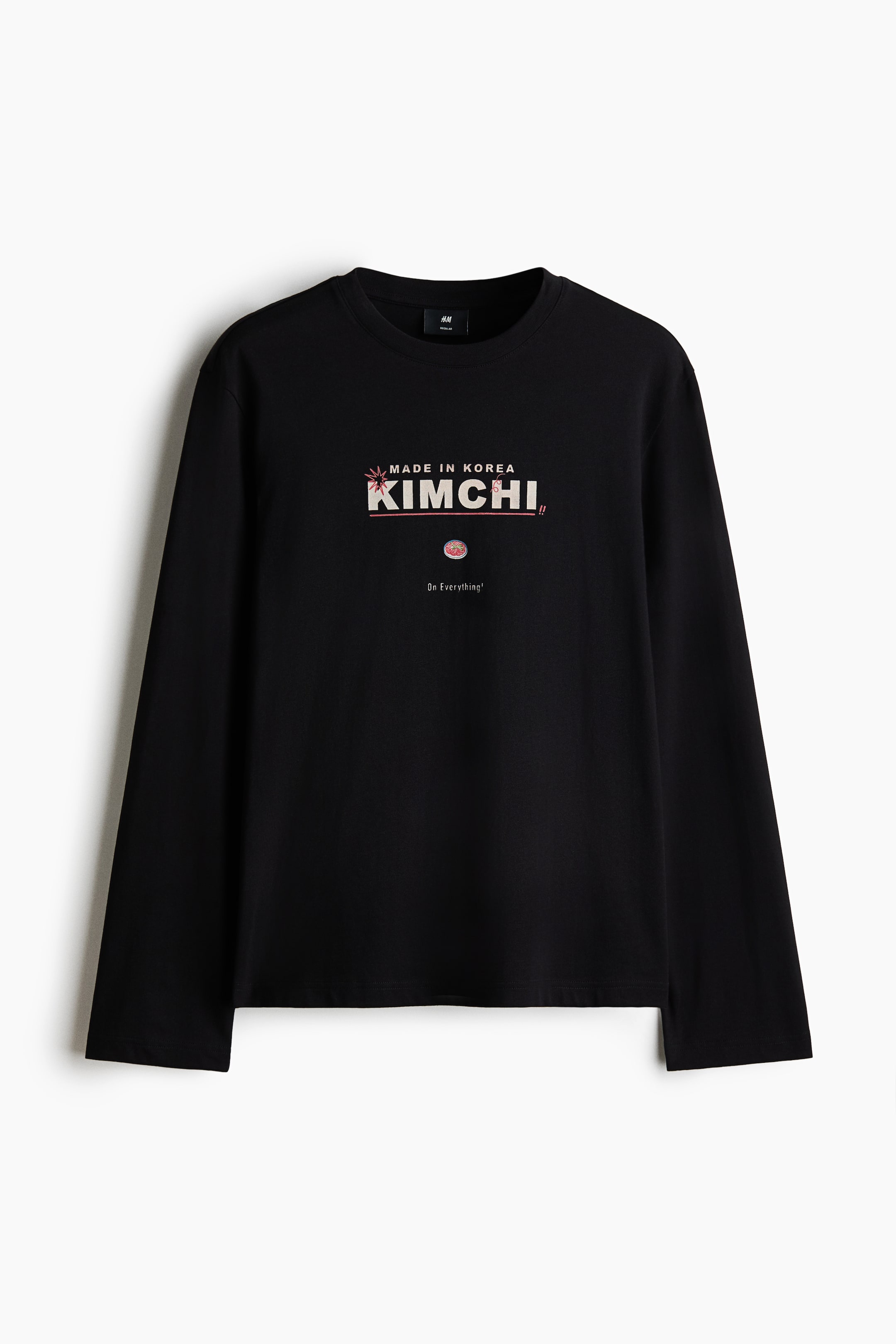 View larger image: A black long-sleeved shirt showcases a graphic print on the front. The print highlights the text "MADE IN KOREA" and "KIMCHI" in a stylized font with reddish accents, accompanied by a small round graphic illustrating kimchi and the text "On Everything!".