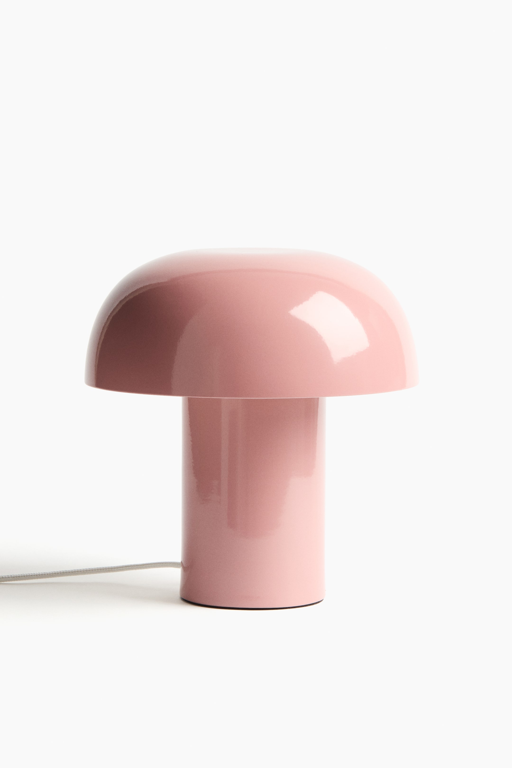 View larger image: A pink metal table lamp is presenting its front view, showcasing a rounded, mushroom-inspired shape with a dome-shaped shade resting on a cylindrical base. 