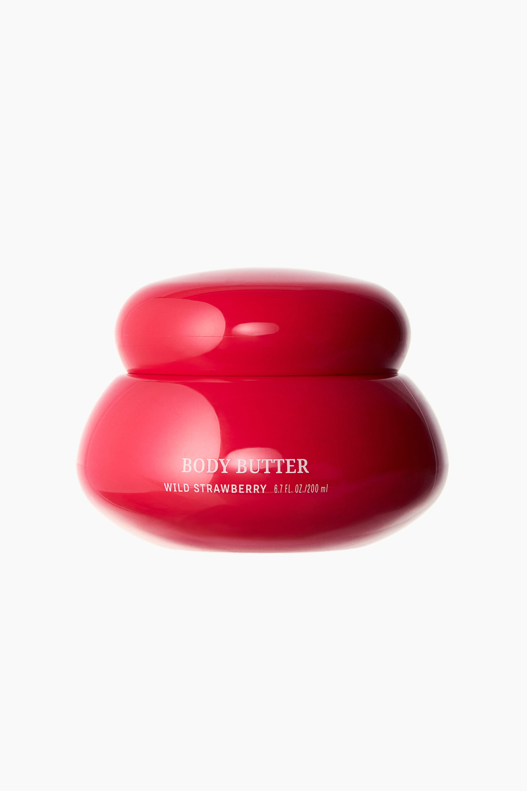 View larger image: A shiny, vibrant red body butter jar is showcased with its front facing forward, highlighting a rounded lid atop a broader, rounded base. White text is visible on the front, stating "BODY BUTTER WILD STRAWBERRY 6.7 FL. OZ./200 ml."