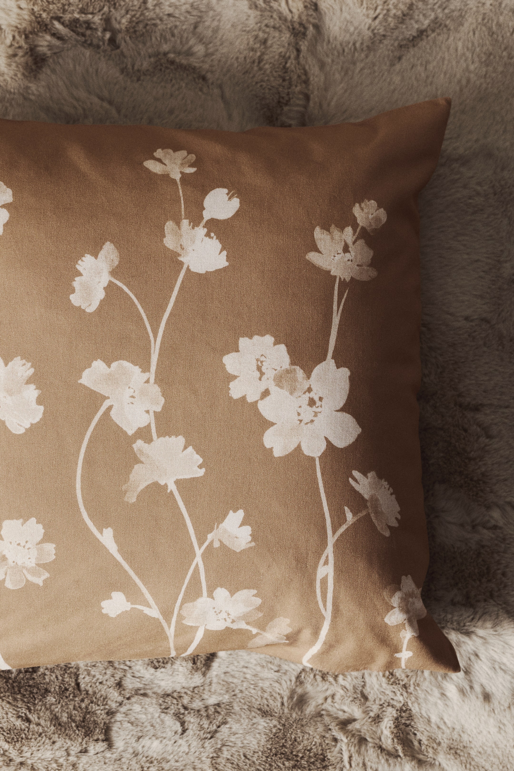 View larger image: A square cushion cover made from brown cotton canvas is displaying a white botanical print of delicate wildflowers across the front.