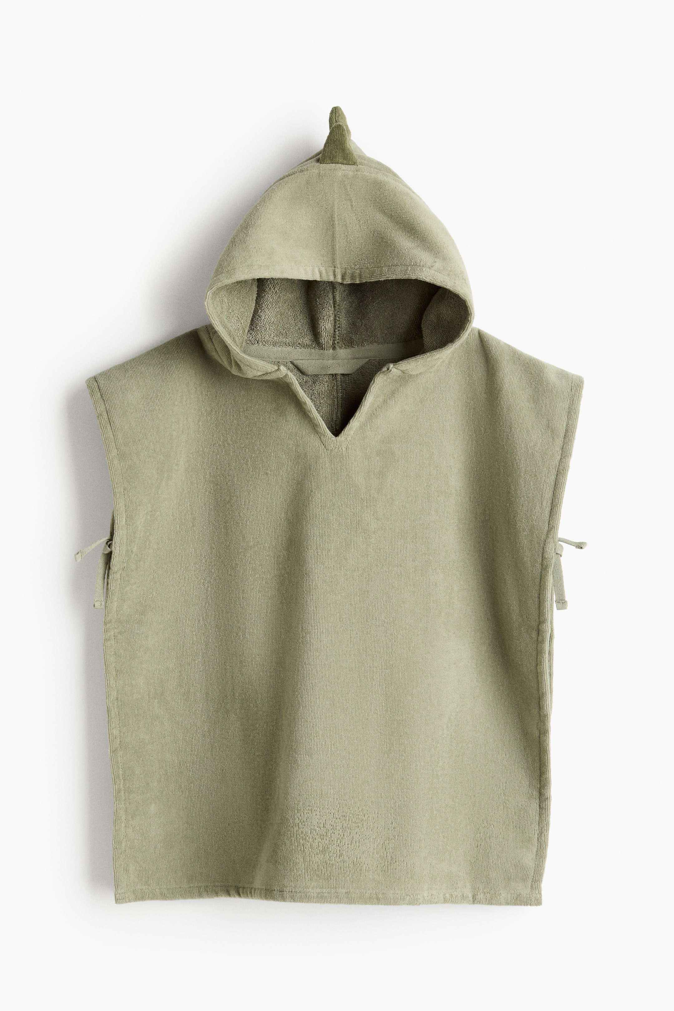 拡大画像を表示: オリーブグリーンのフード付きタオルポンチョは、Vネックの開きとフード上部に小さな尖ったフィン状のディテールをあしらっています。小さな紐がポンチョの両側から伸びています。