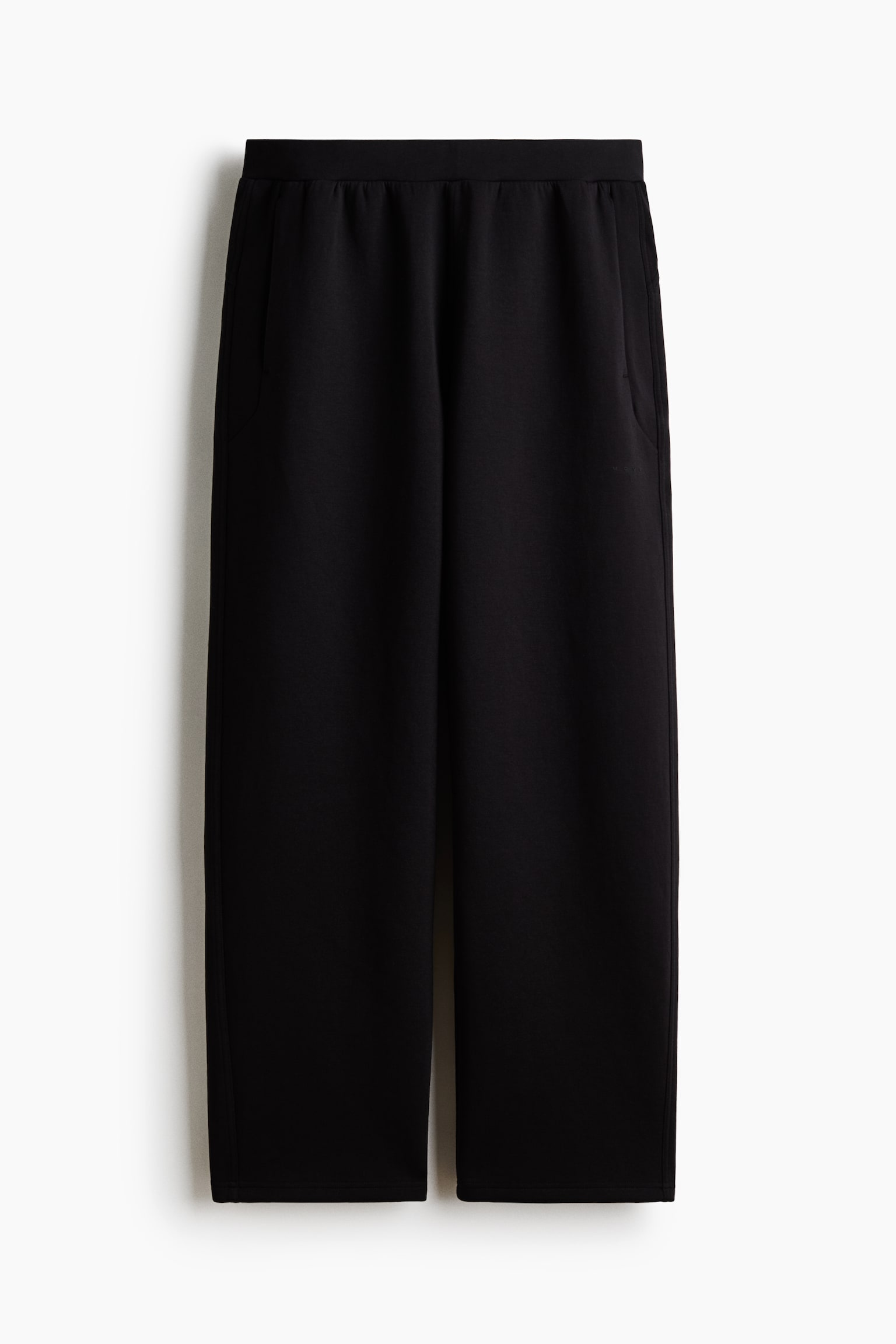 Black pants are featuring a straight, wide-leg cut, an elasticated waistband, and slanted side pockets. - 1