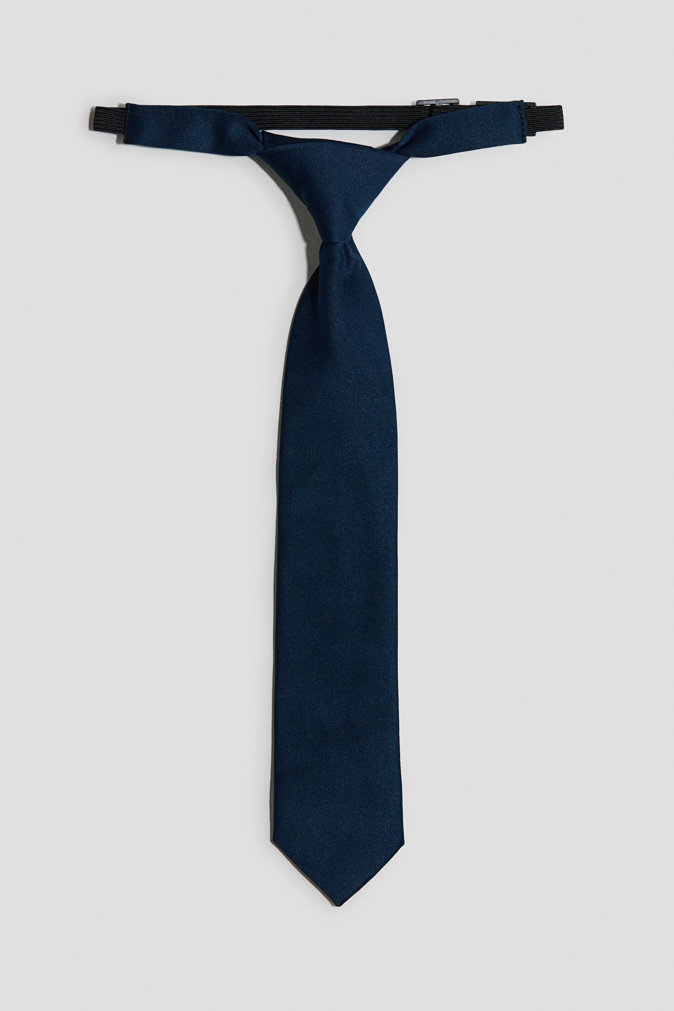 View larger image: A navy blue pre-tied necktie is presented facing front, featuring a neat knot and a pointed blade. An adjustable black elastic strap is visible at the top, attaching behind the knot.