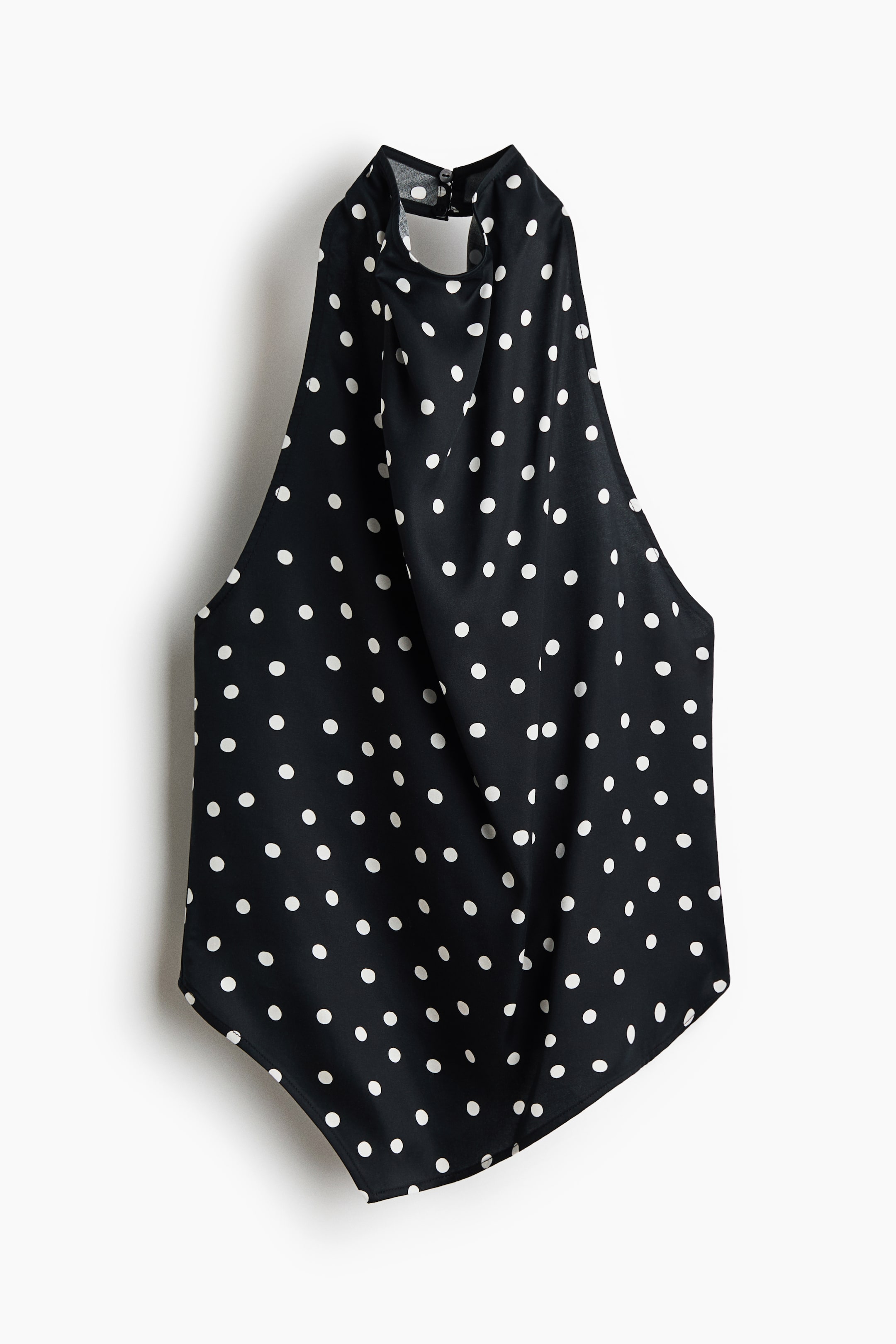 Voir une image plus grande: Un haut licou noir à pois blancs est suspendu pour mettre en valeur son design de face. Il présente un col montant drapé qui se ferme au dos, une coupe sans manches et un corsage fluide et décontracté avec un ourlet arrondi.