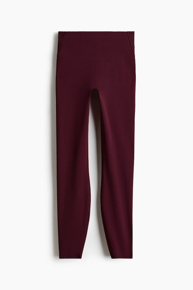 Leggings rojo oscuro que presentan un diseño de cintura alta con una pretina ancha. Están confeccionados con una tela suave y tienen un corte largo completo, ajustándose hasta los tobillos. - 1