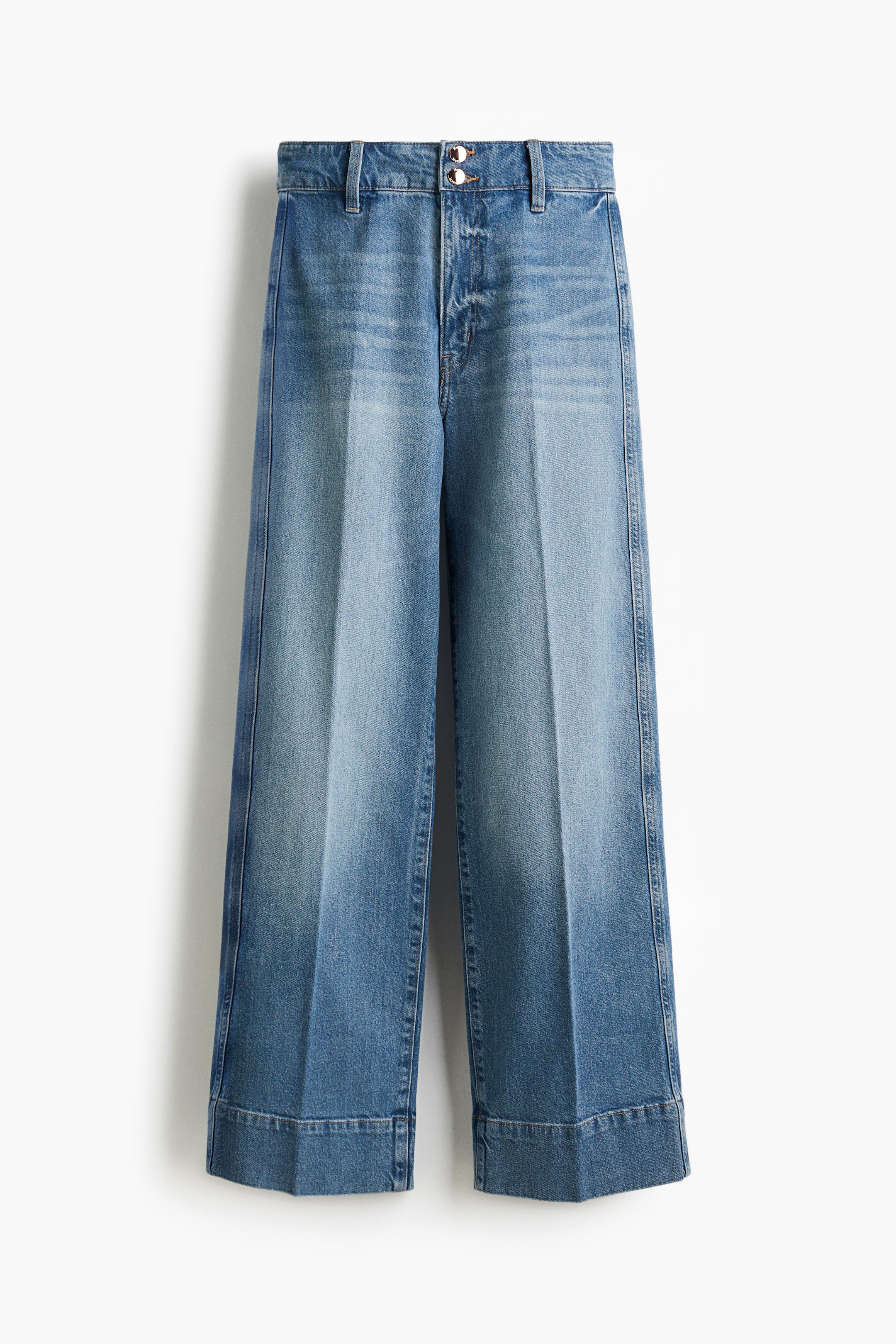 Visualizza immagine più grande: Vista FRONTALE di un paio di jeans in denim azzurro chiaro. Presentano una vita alta con zip e due bottoni, e un taglio a gamba larga che si estende dalla coscia fino a un orlo ampio. Pieghe prominenti corrono lungo la parte anteriore di ciascuna gamba, e i jeans mostrano una lunghezza lunga con ampi risvolti piegati.