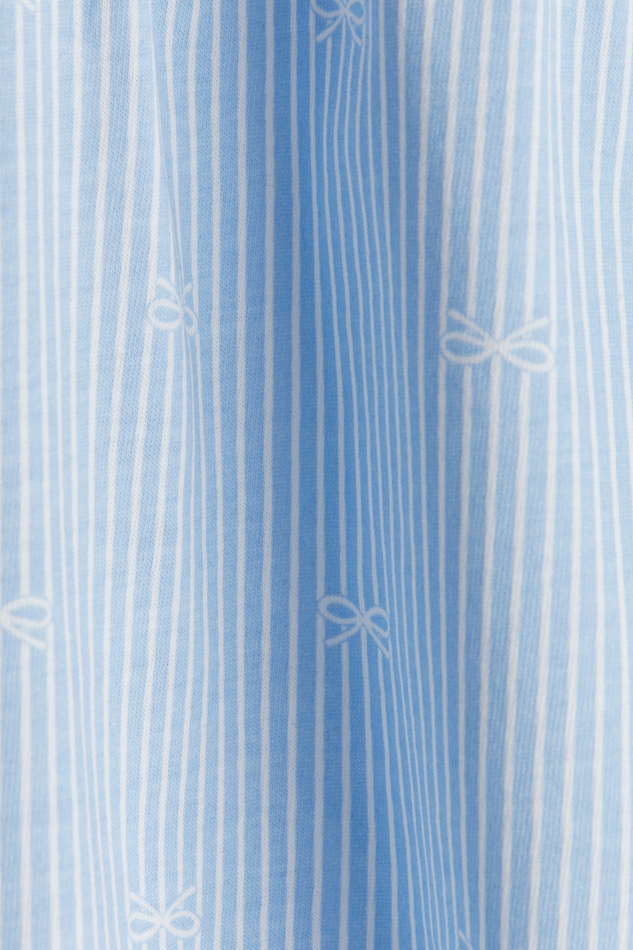 Größeres Bild ansehen: Das Kleid aus weichem, bedrucktem Baumwolljersey zeigt blau-weiße vertikale Streifen. Kleine weiße Schleifenmuster wiederholen sich im gestreiften Material.