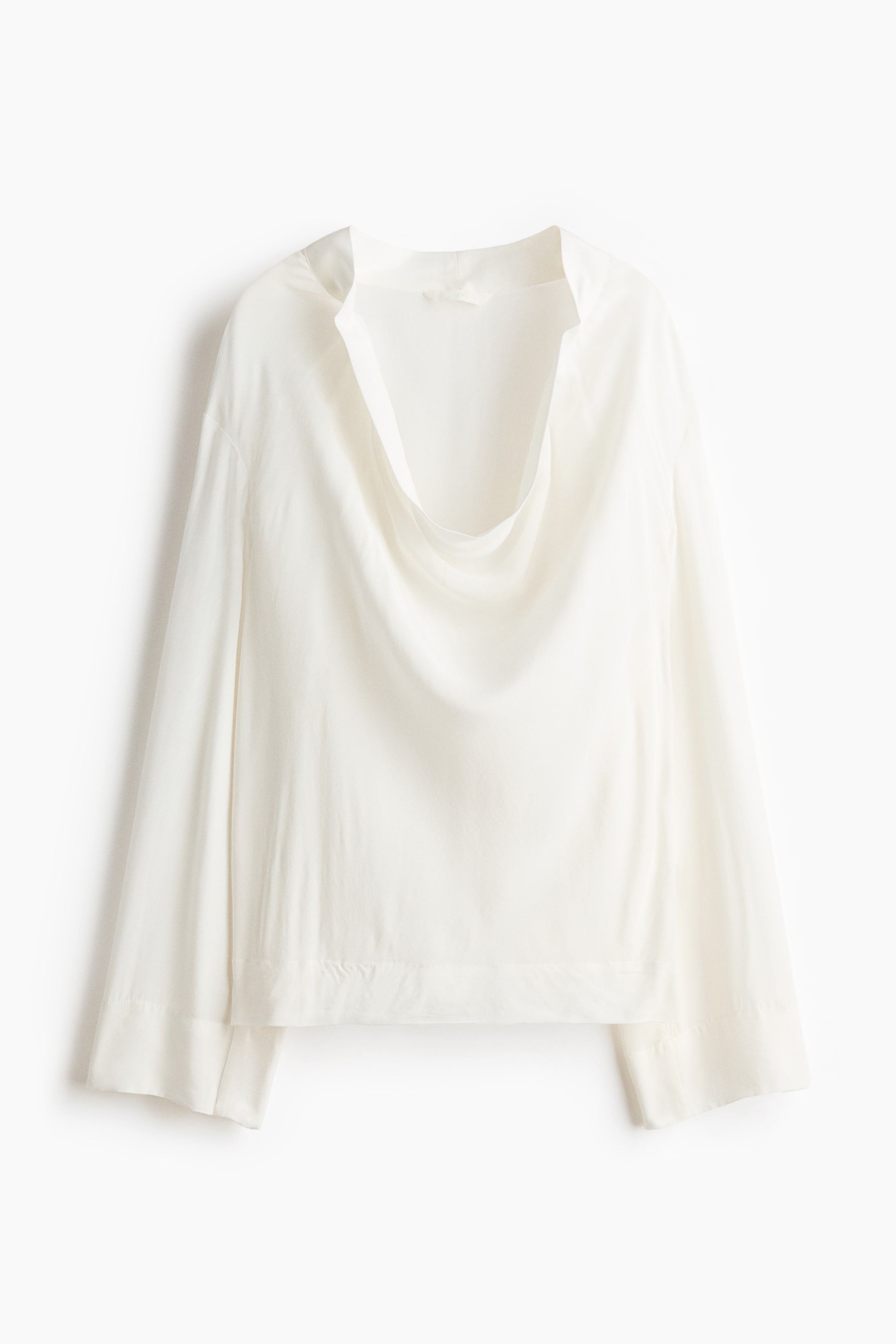 View larger image: "A white blouse is displayed front-facing, featuring a wide, draped cowl neck and long, wide sleeves. It showcases a loose fit and a straight hemline with a subtle band at the bottom."