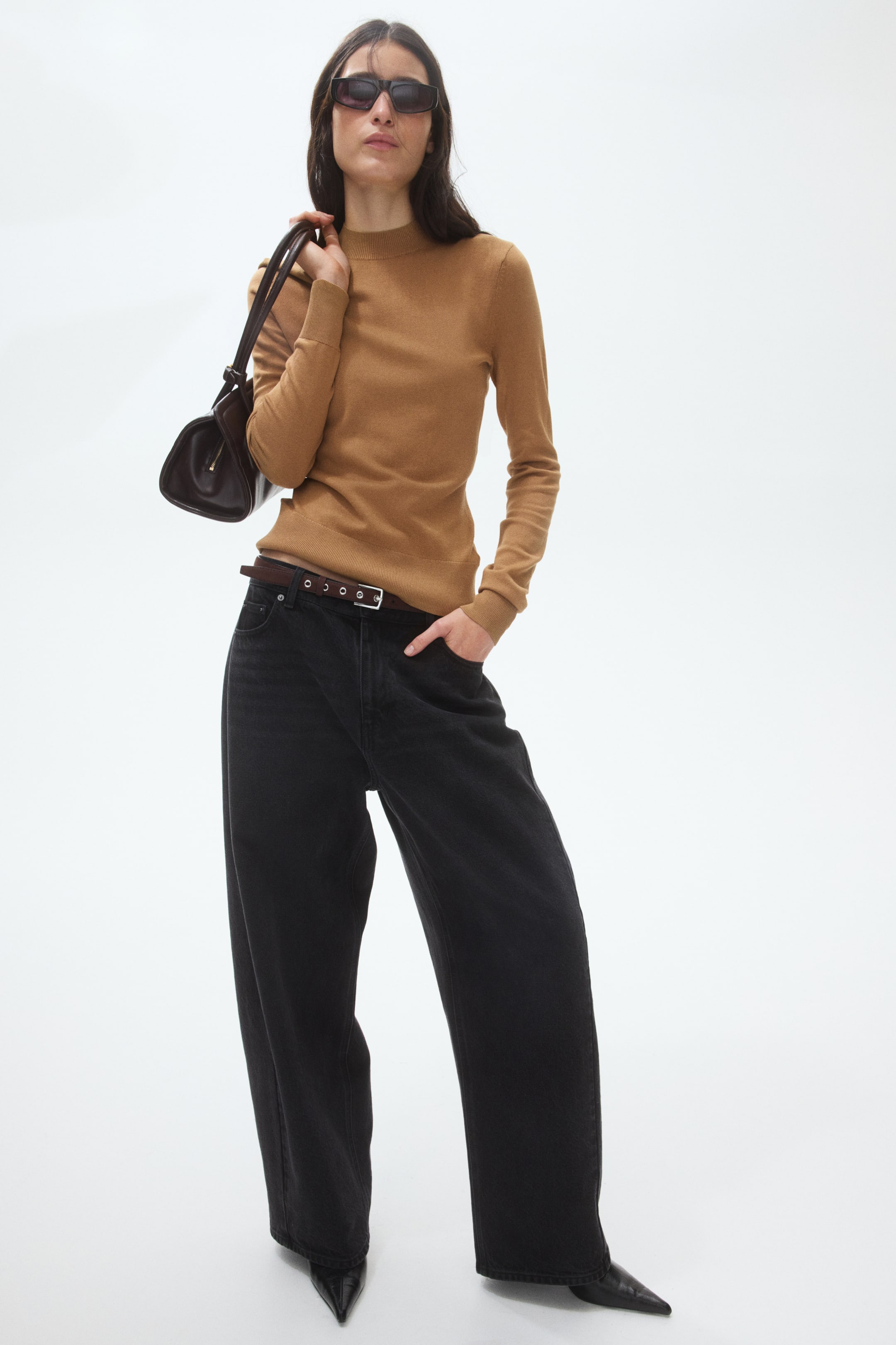 View larger image: A brown mock-neck jumper features a smooth, fine-gauge knit with a close-fitting mock neckline and long sleeves, its fitted hemline tucked into dark jeans.
