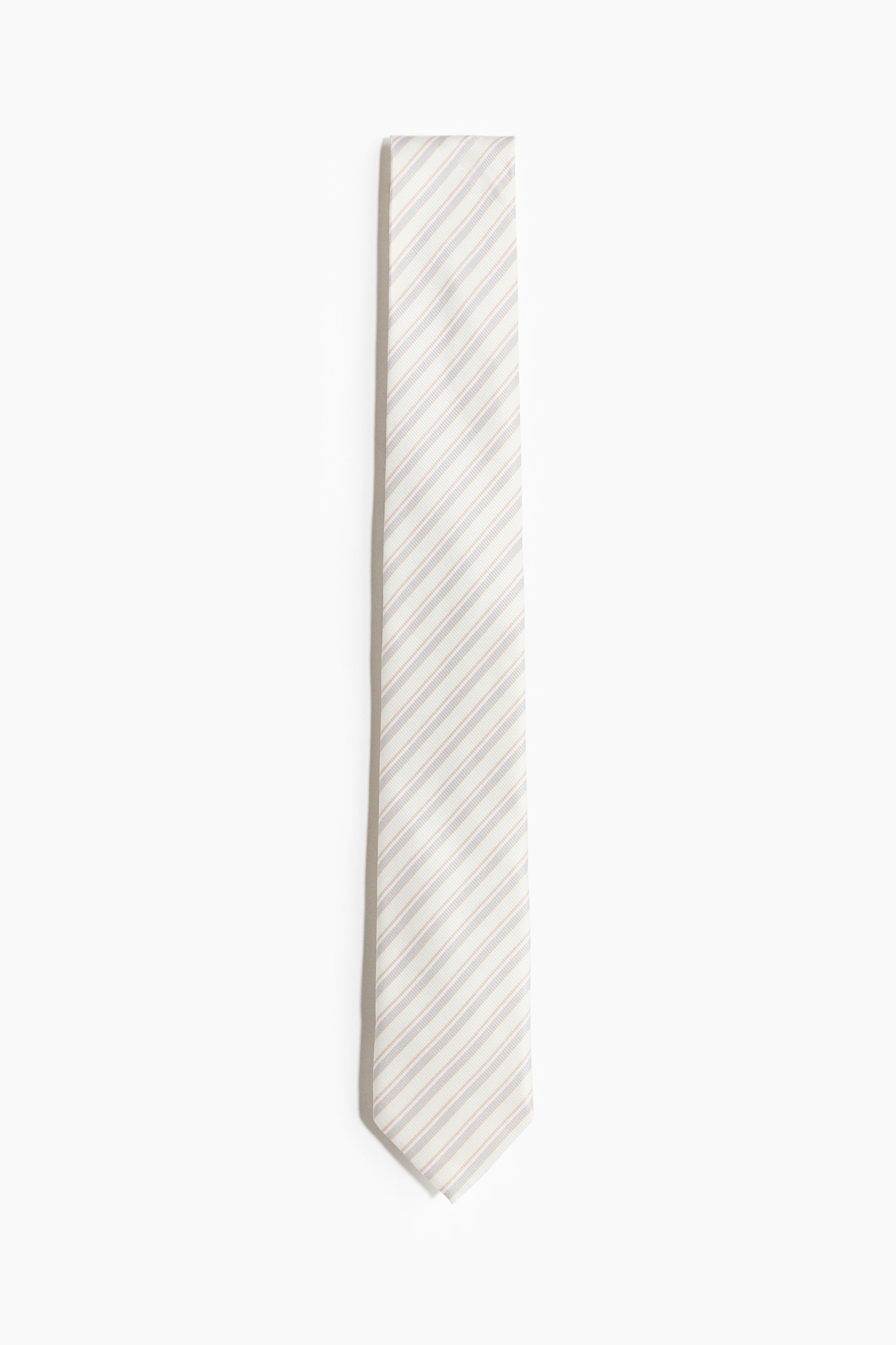 View larger image: A tie is laid flat, showcasing its front side. It features thin diagonal stripes in alternating light blue and light brown tones on an off-white background, with its pointed bottom tip visible.