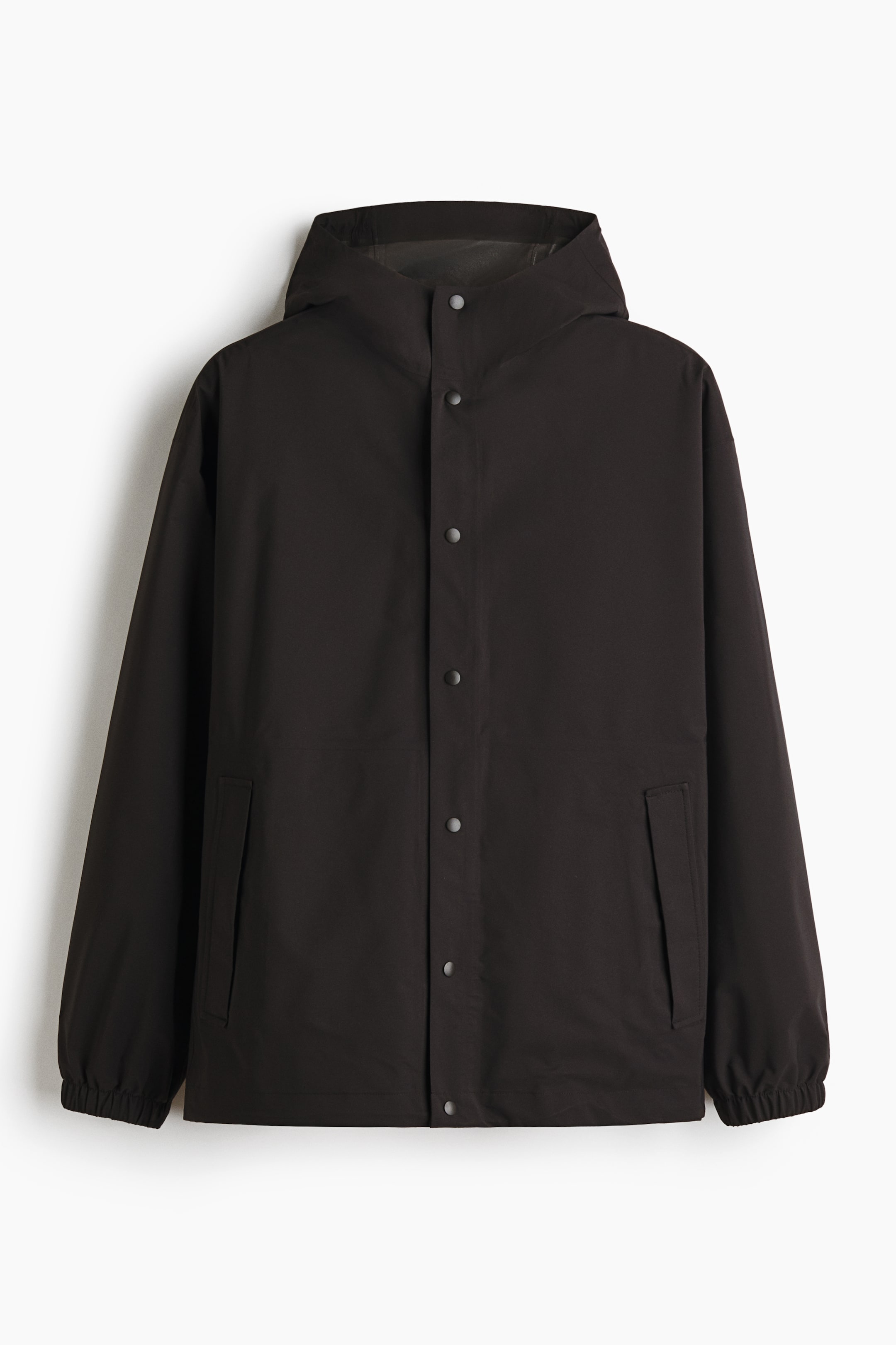 Ver imagen más grande: La chaqueta impermeable con StormMove? se presenta en su vista frontal. Presenta un tejido de color oscuro con un acabado mate, una tapeta completa de botones a presión con botones de tono plateado y una capucha integrada. En la parte inferior delantera se aprecian puños elásticos y dos bolsillos de ojal inclinados.