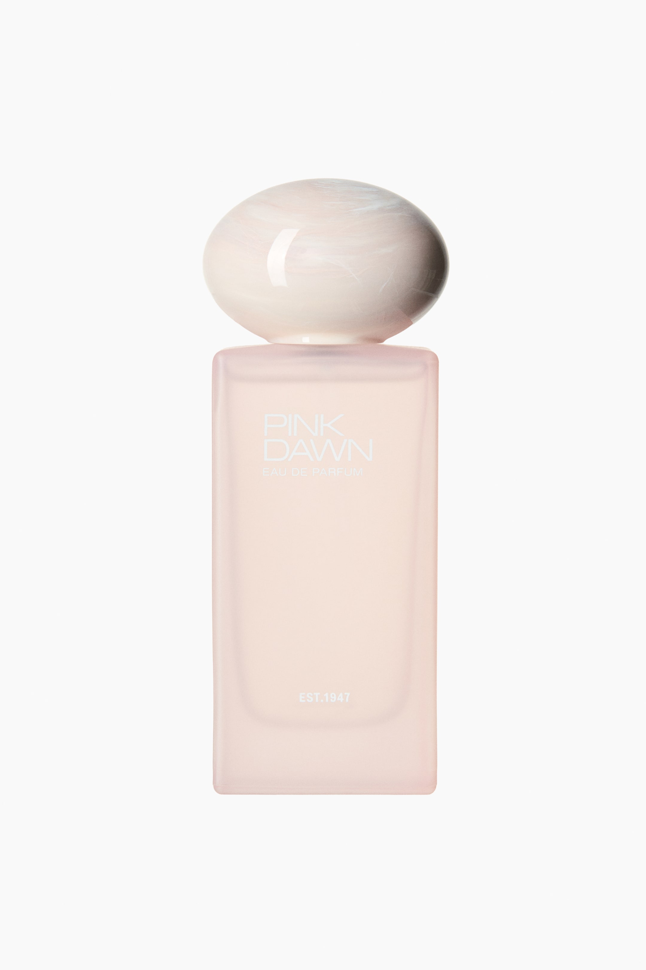 Visa större bild: Pink Dawn EdP har en rektangulär flaska i frostat ljusrosa glas, vänd framåt. Den är toppad med en stor, rundad kork som visar ett mönster i vitt och ljusrosa marmor, medan 'PINK DAWN', 'EAU DE PARFUM' och 'EST.1947' är tryckta på framsidan.
