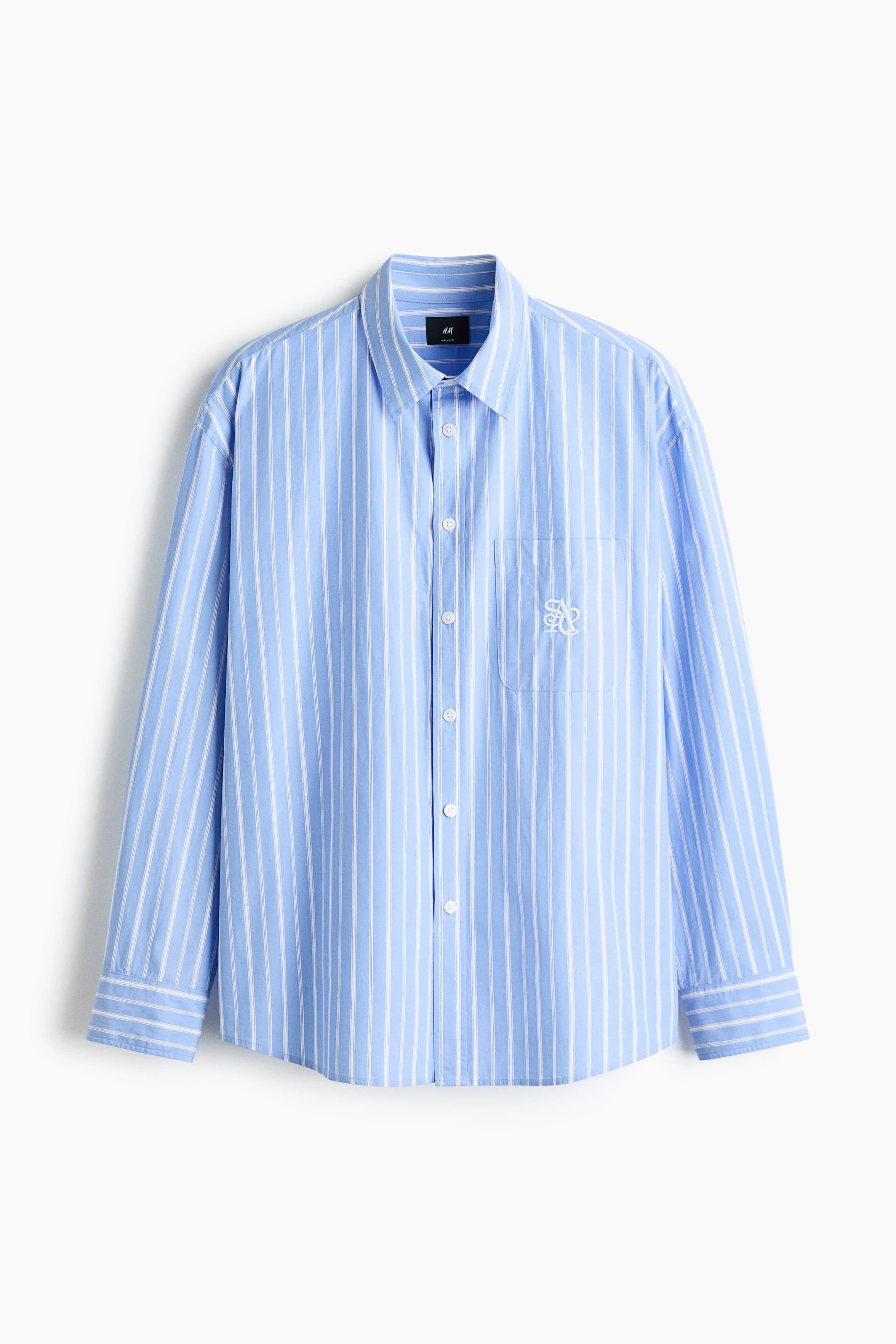 View larger image: A light blue shirt with white vertical stripes showcases its FRONT, featuring a pointed collar, a full-button placket with white buttons, a left chest patch pocket with a white embroidered monogram, and long sleeves with buttoned cuffs.
