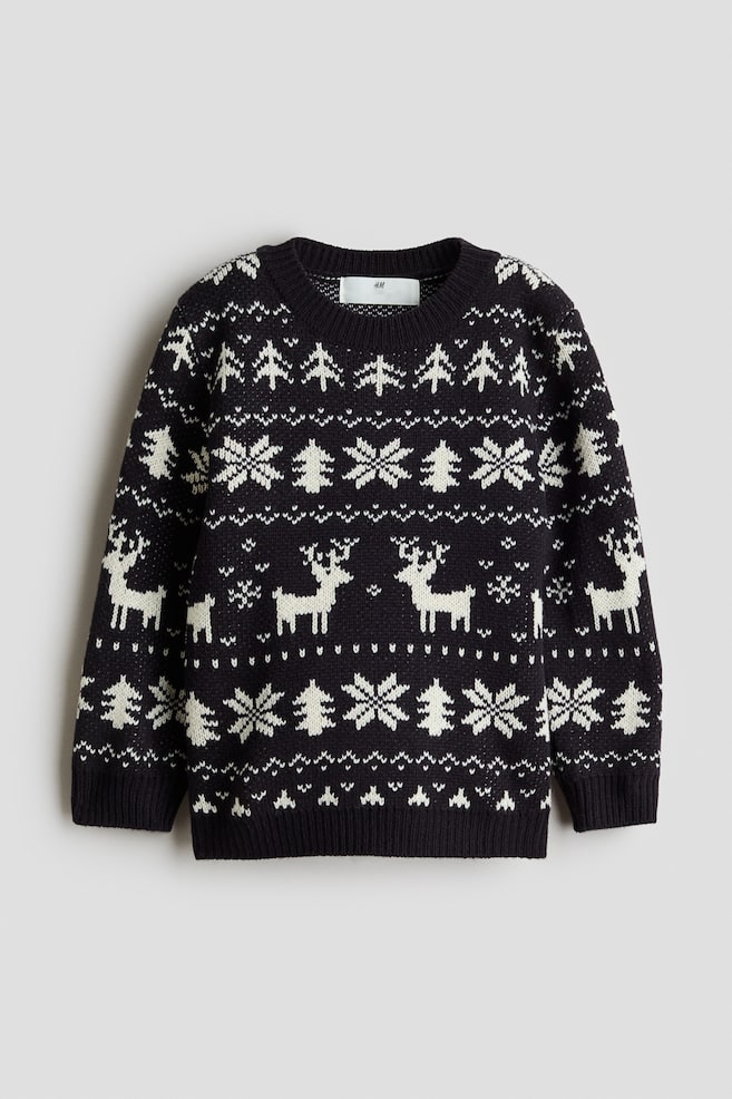 A long-sleeved jacquard-knit sweater is shown front-facing, featuring a dark navy and white pattern of reindeer, snowflakes, and pine trees. The sweater has a round, rib-trimmed neckline, ribbed cuffs, and a ribbed hem. - 1