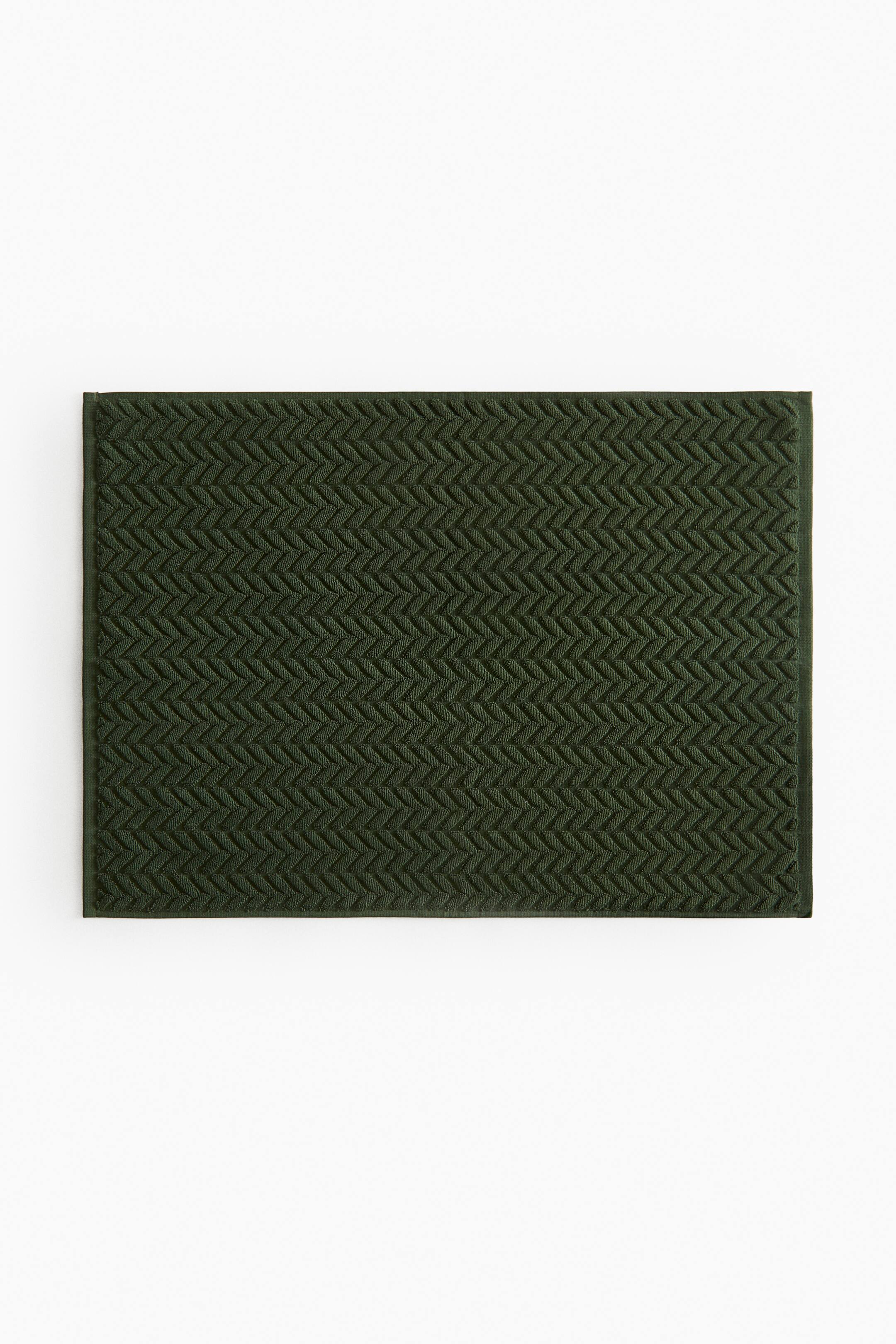 View larger image: A dark green rectangular mat lies flat, featuring a raised chevron pattern across its entire surface.