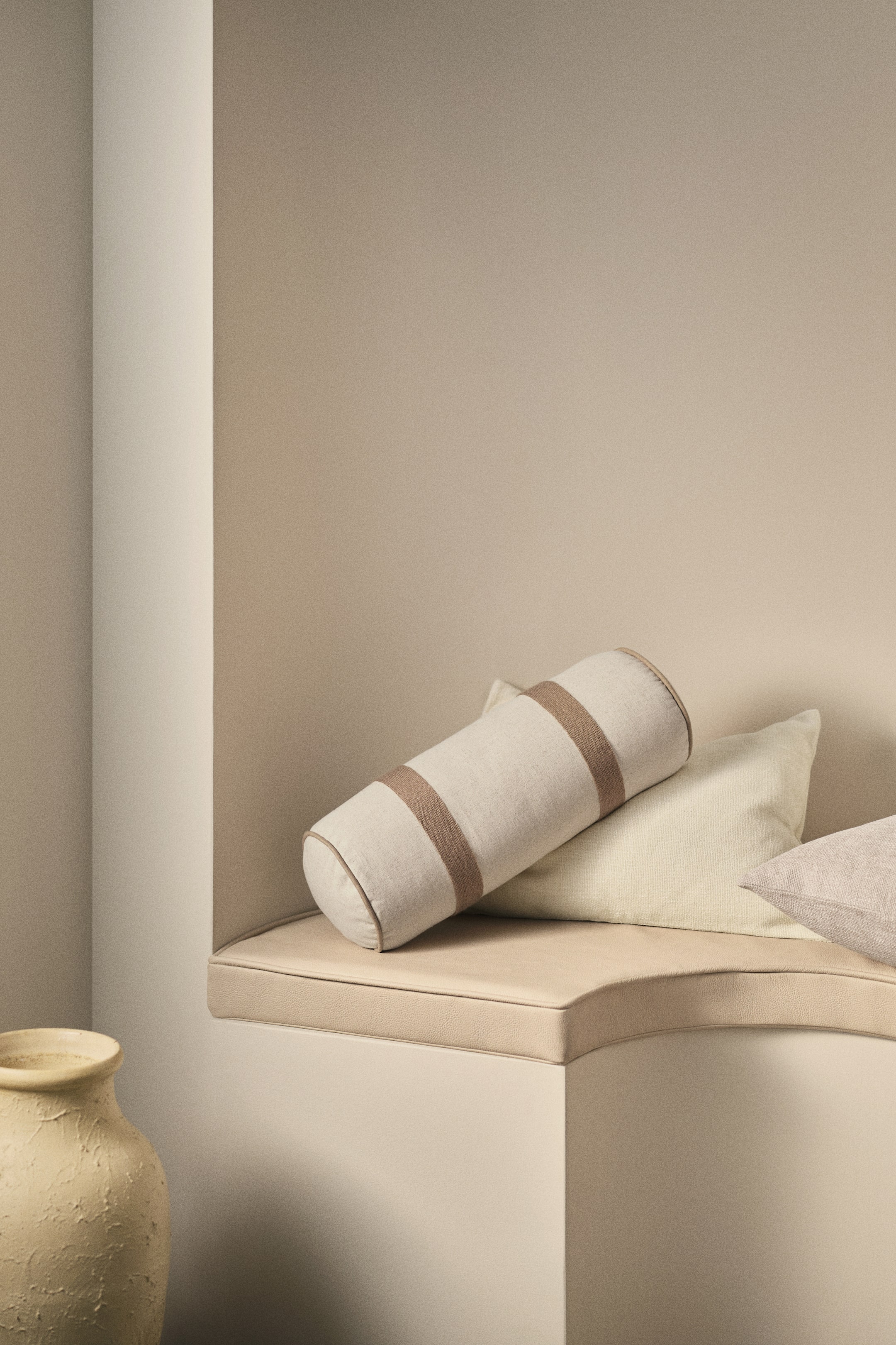 View larger image: A bolster crafted from a rustic linen and cotton blend weave, showcasing broad, embroidered brown stripes along with piping at its edges.