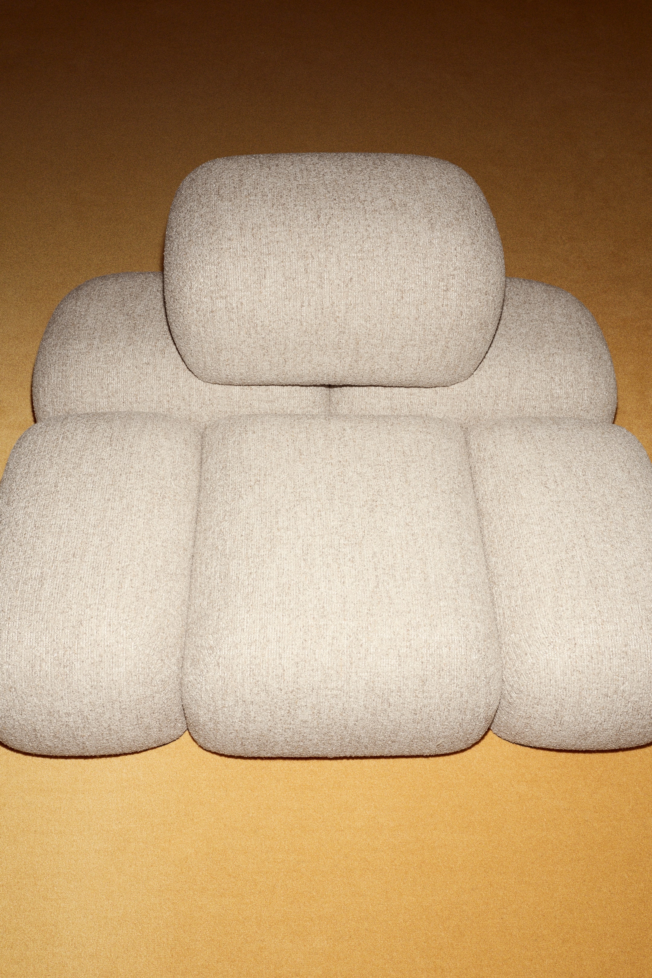 Ver imagen más grande: La silla lounge Soluna se presenta en una vista frontal, mostrando un diseño modular con cojines redondeados y mullidos. Está tapizada en una tela texturizada de color beige claro, con un gran cojín reposacabezas situado sobre varios cojines más pequeños para el respaldo y el asiento.