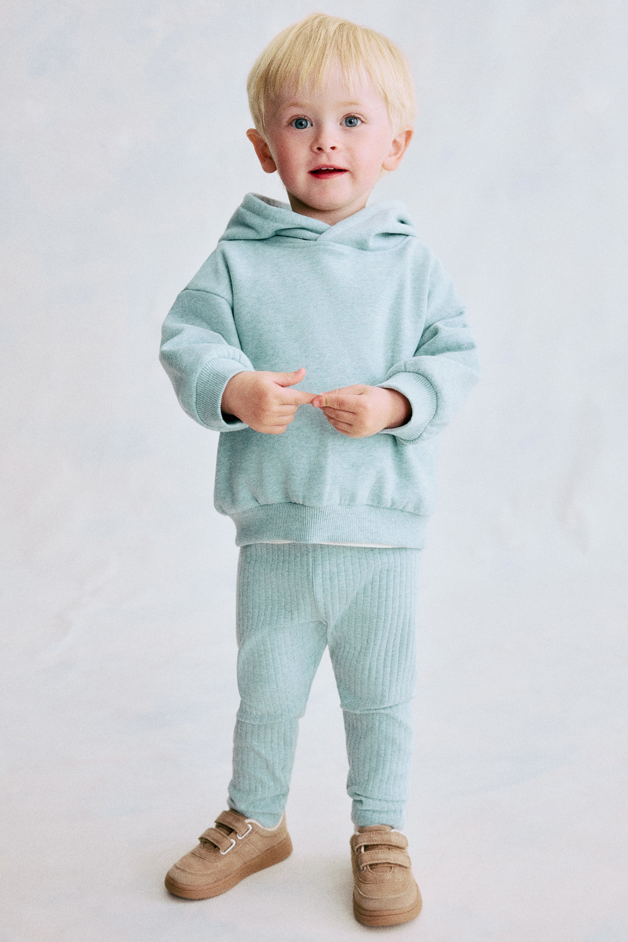 View larger image: A light blue two-piece set is presenting, consisting of a long-sleeved hoodie with a hood, ribbed cuffs, and a ribbed hem. The matching light blue pants are showcasing a vertical ribbed texture throughout.