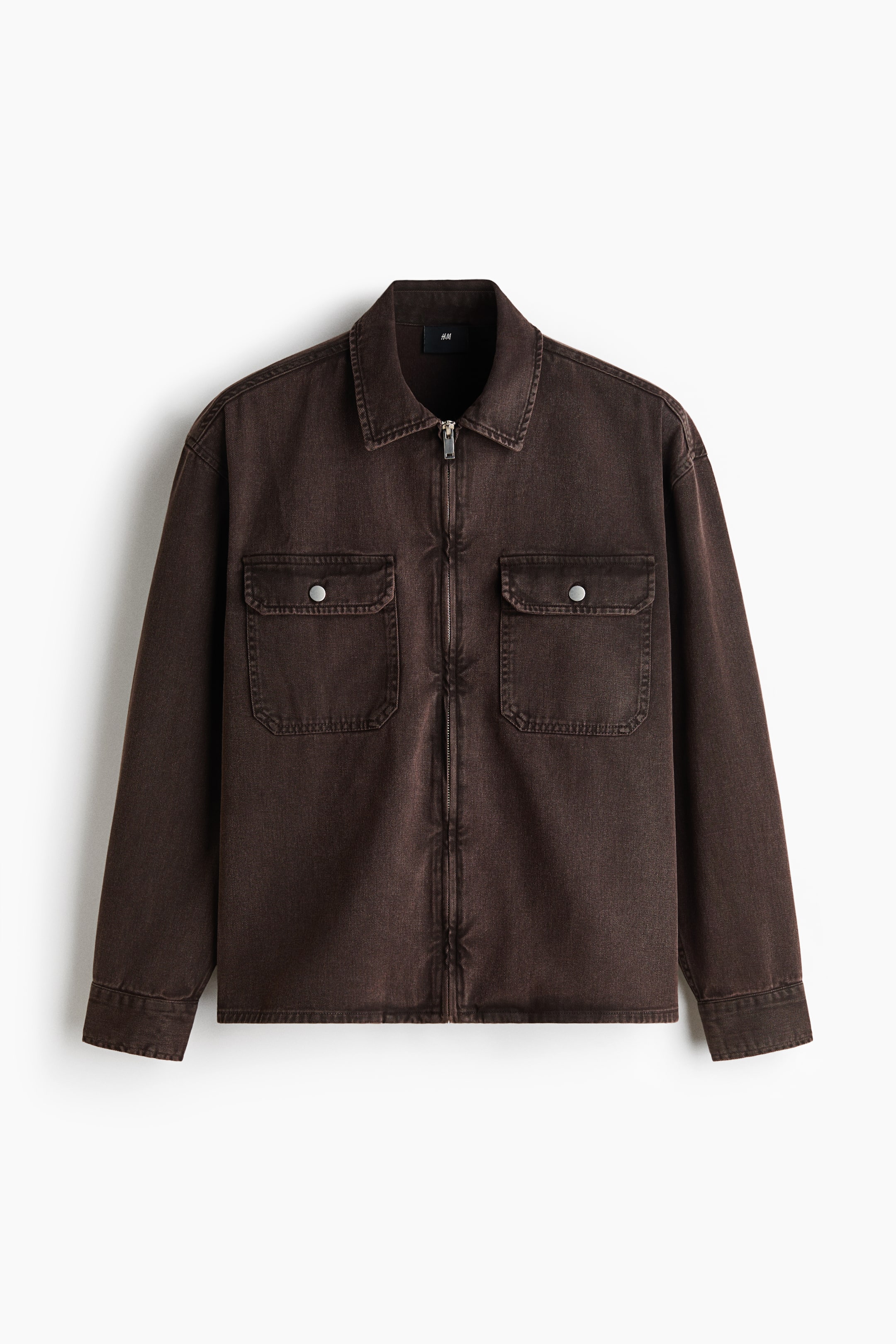 View larger image: A dark brown, washed utility jacket is shown from the front, featuring a full-length silver zip closure, a pointed collar, and two chest patch pockets with silver snap closures.