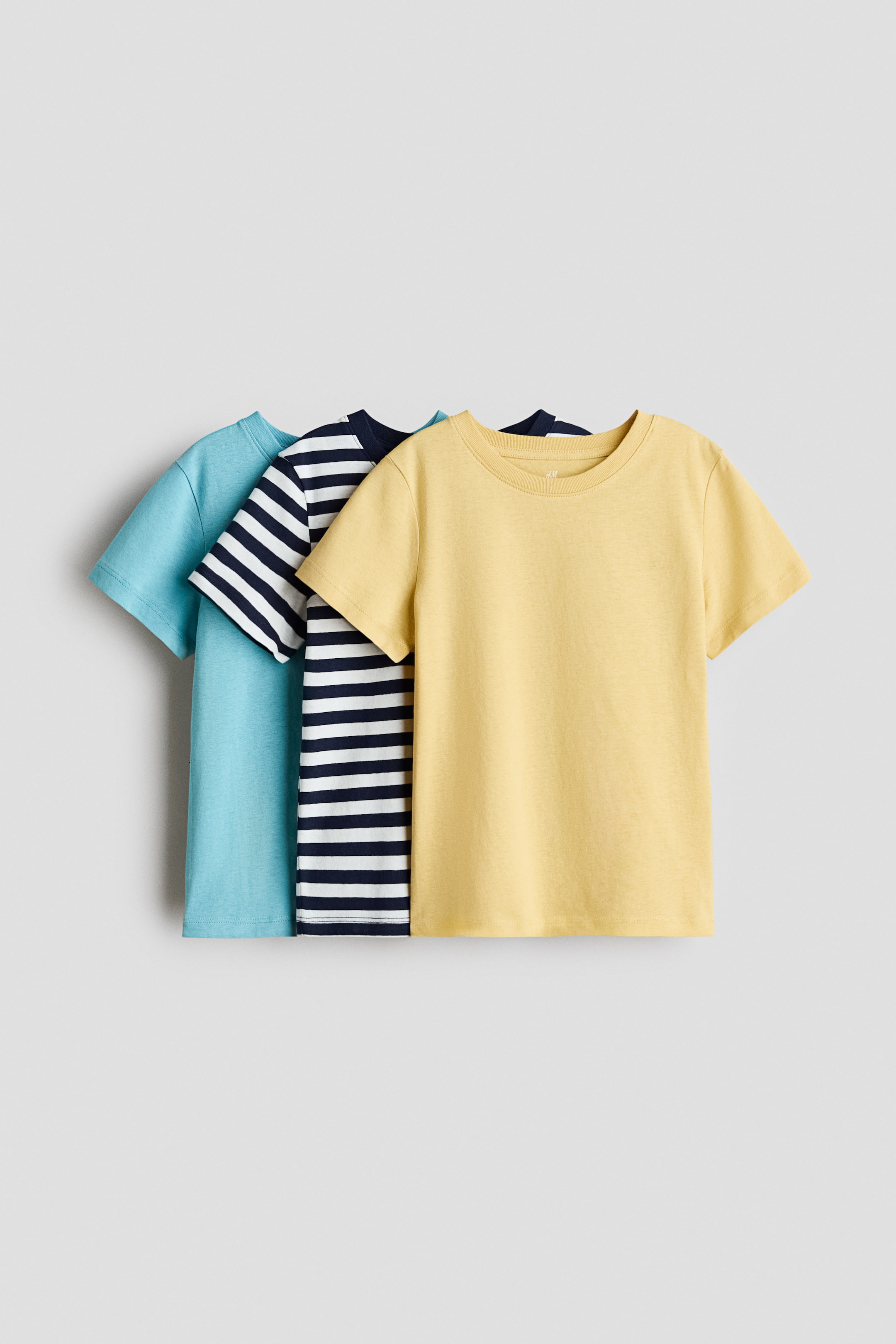 View larger image: Three t-shirts are layered from left to right, showcasing their front views. The leftmost is a solid light blue, the middle features a navy blue and white horizontal stripe, and the rightmost is a solid yellow. All t-shirts boast a round, rib-trimmed neckline and short sleeves.