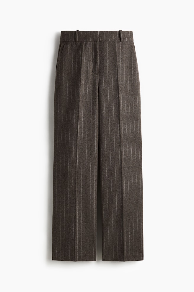 Charcoal gray pinstripe trousers are presented front-facing, displaying a flat waistband with belt loops and two prominent front pleats on each leg, creating a structured, straight-leg fit with a visible center crease. - 1