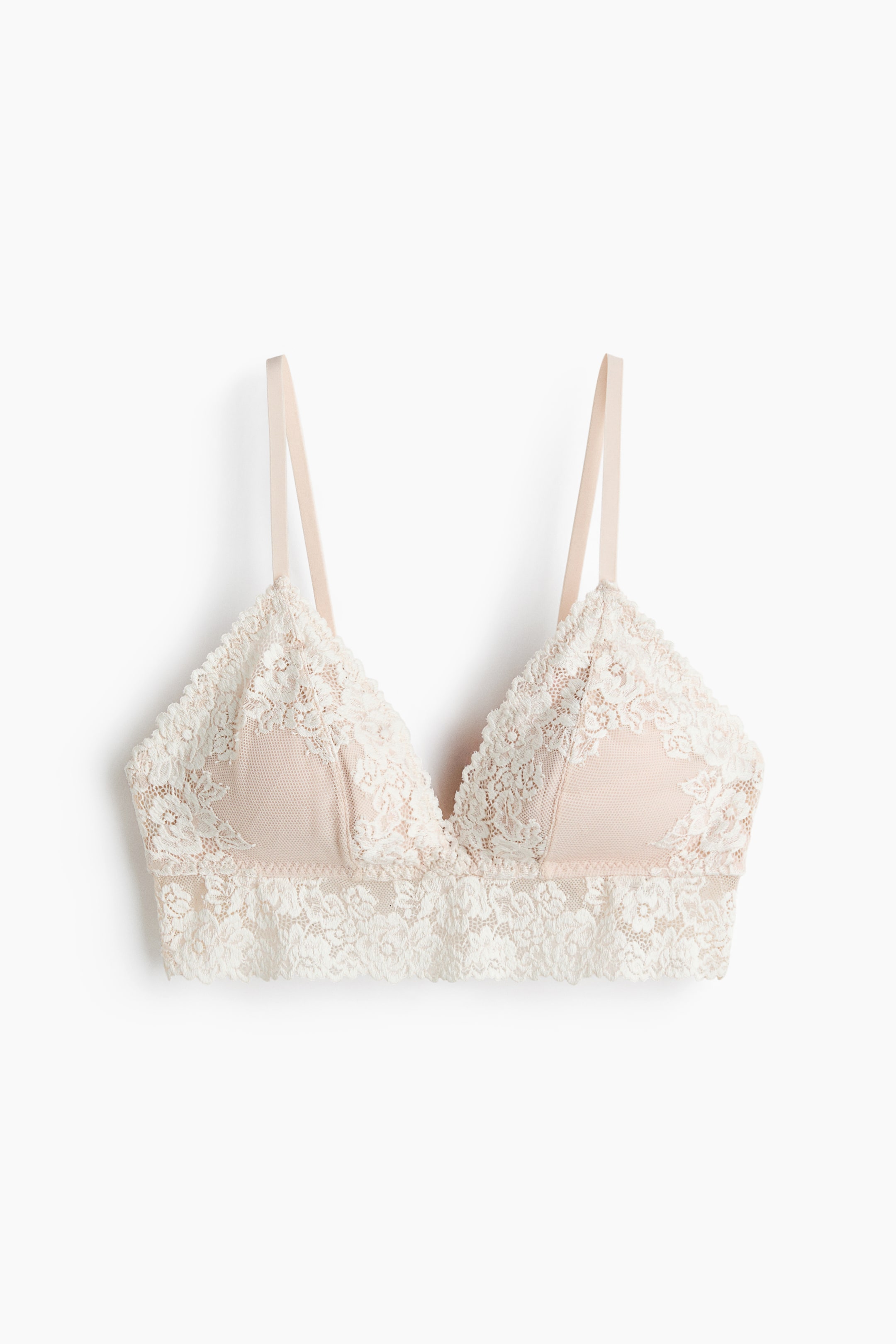 Xem ảnh lớn hơn: Một chiếc bralette đang nằm phẳng, nổi bật với chi tiết ren hoa màu trắng ngà trên lớp lót màu nude. Nó có cúp hình tam giác với viền ren hình vỏ sò và dây đeo vai mỏng có thể điều chỉnh.