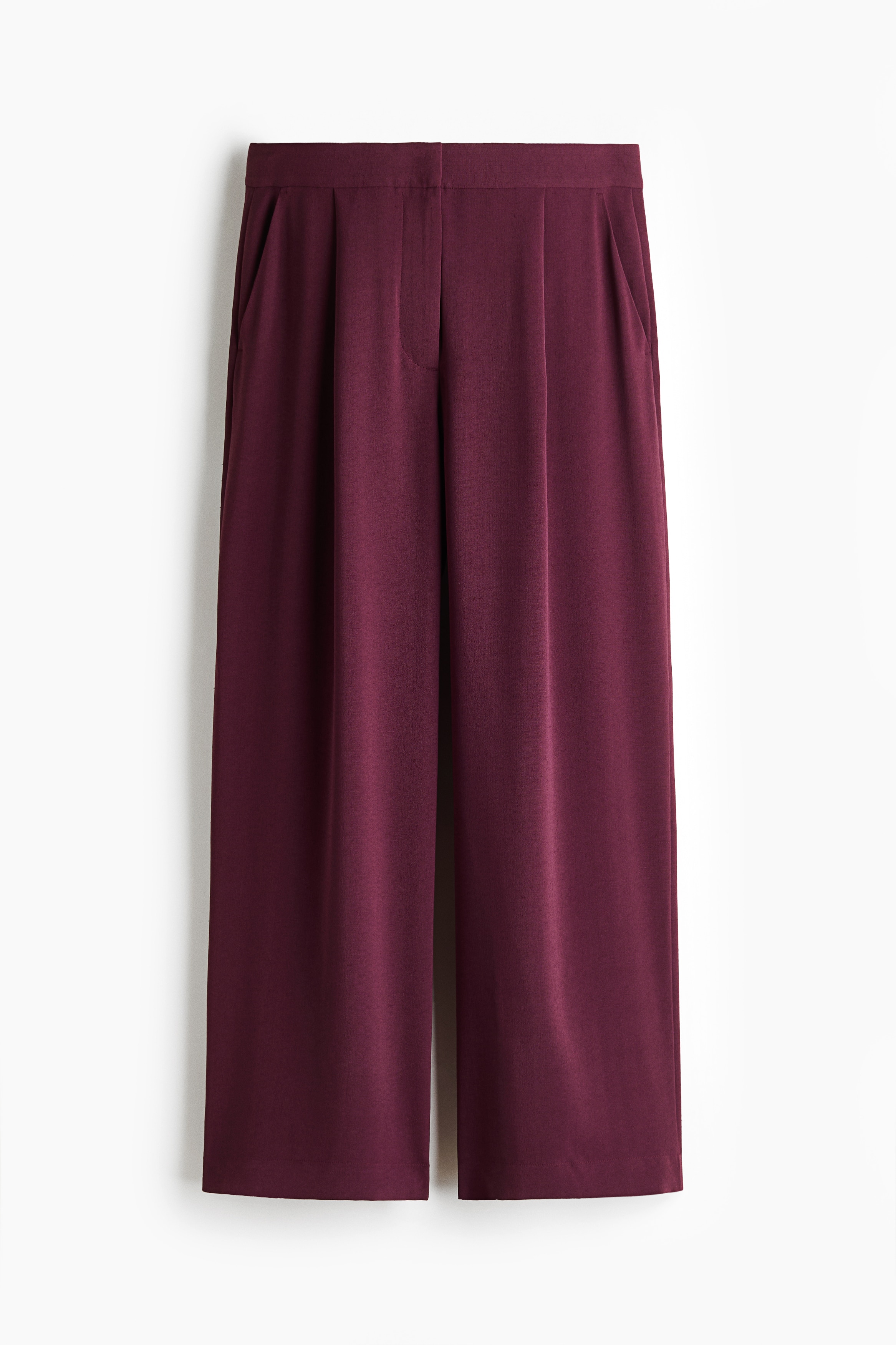 Relaxed-fit, wide-leg pants in a deep plum woven fabric are being worn by the model, who is standing and facing forward. The pants are styled as a matching set with a long-sleeve belted wrap jacket and black flat slide sandals.
