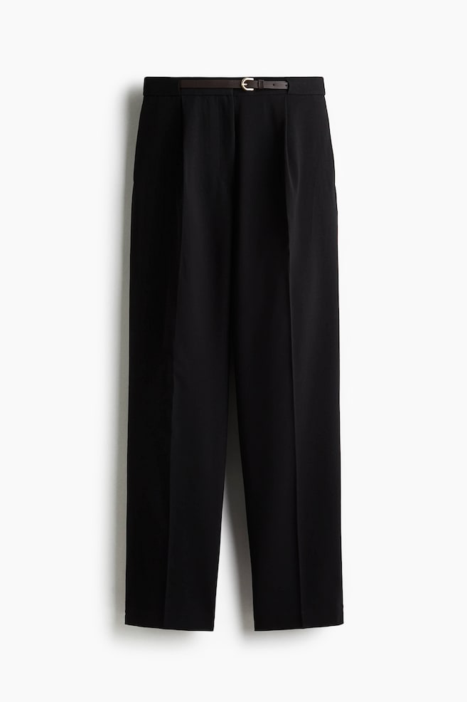 Loose-fit, tailored black trousers are being shown from the FRONT, featuring a high waist. A narrow, dark belt with a gold-tone buckle is cinching the waist. Pleats are forming from the waistband, and creases are running down the center front of each tapering leg. - 1