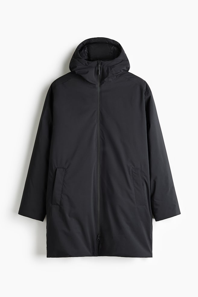 A black mid-length hooded jacket is shown from the front, featuring a smooth matte fabric, a full-length front zip, and an integrated high-neck hood. The jacket features two vertical welt pockets and long sleeves with clean-finished cuffs. - 1