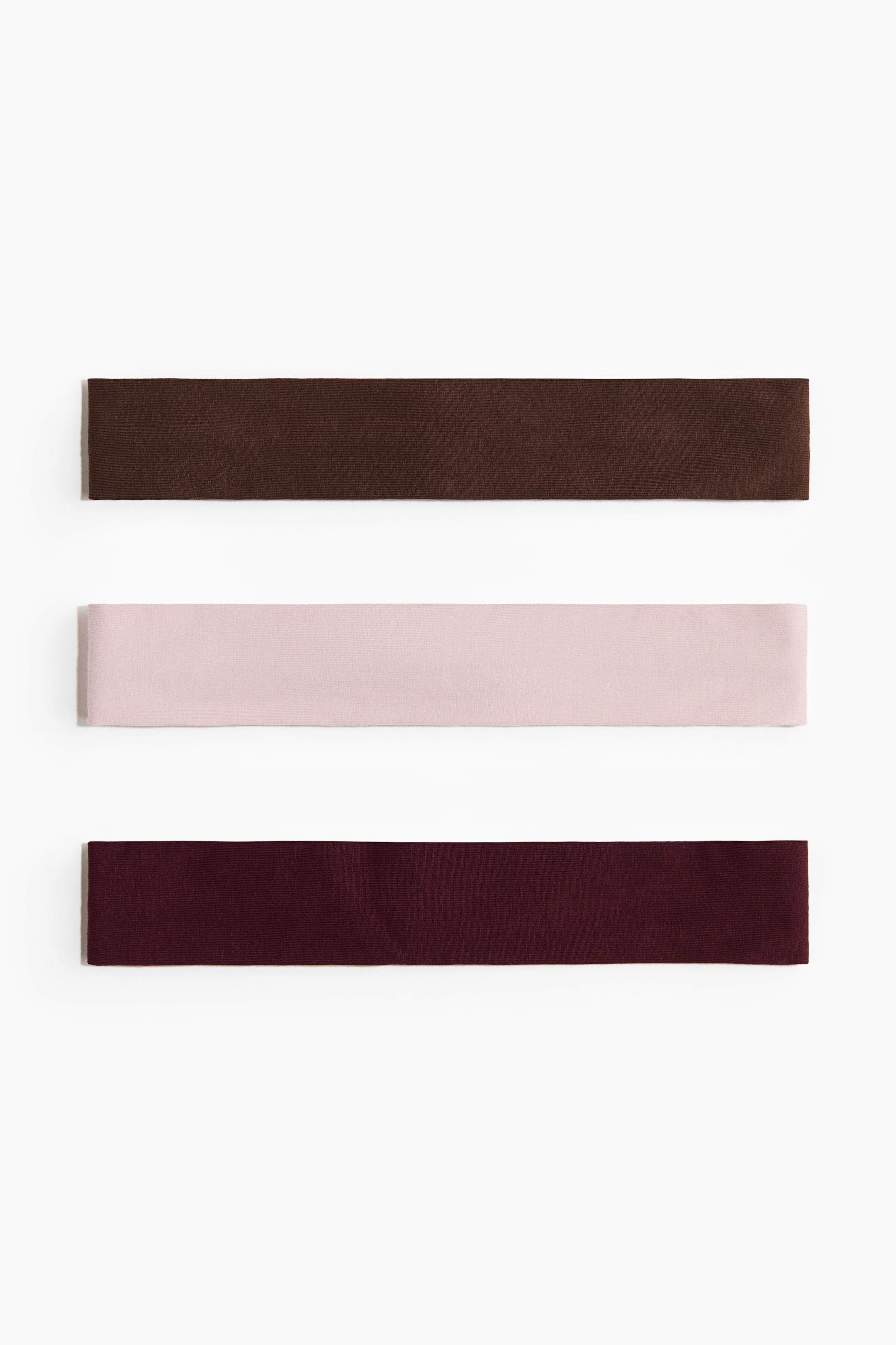 View larger image: "Hairbands in soft cotton jersey are showcased as three flat bands, available in dark brown, light pink, and dark maroon hues, each boasting a smooth, matte finish."