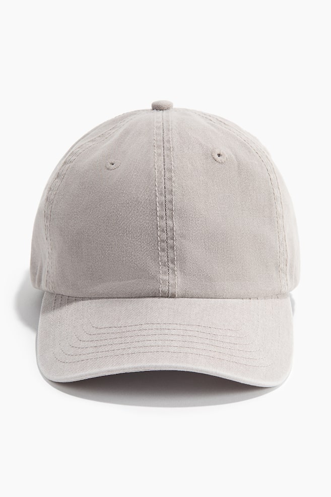 A cotton twill cap is facing front, showcasing a rounded crown with a top button and ventilation eyelets, above a curved brim with horizontal stitch lines. - 1