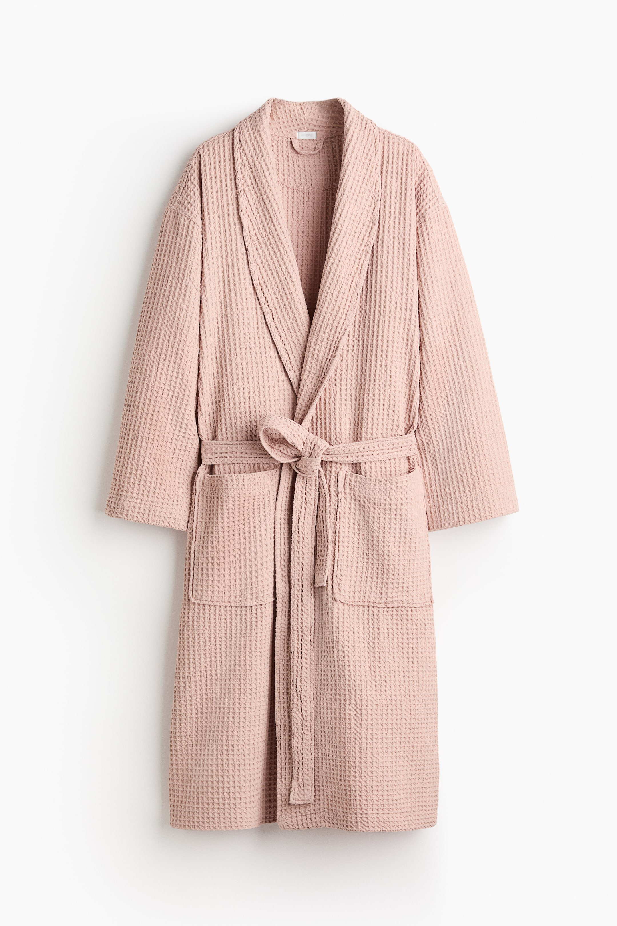View larger image: A light pink dressing gown is presenting from the FRONT, featuring a waffle-weave texture and wide shawl lapels. It is designed with two patch front pockets and a tie belt that is knotted at the waist.