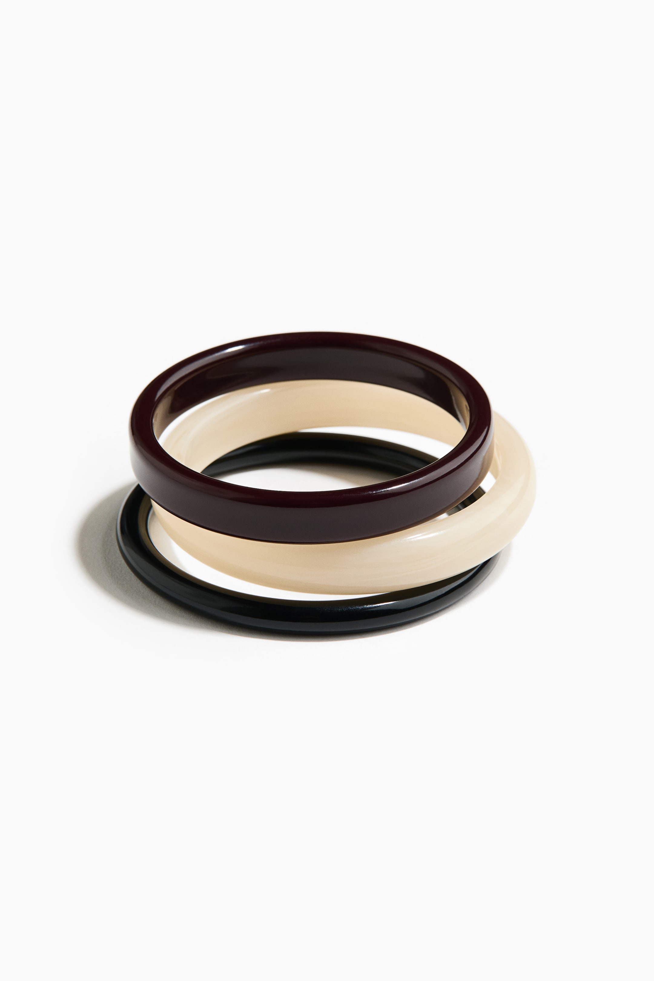 Ver imagen más grande: Tres pulseras se apilan juntas, presentando una pulsera marrón oscuro, una crema y una negra. Cada pulsera muestra una superficie de plástico brillante y lisa.
